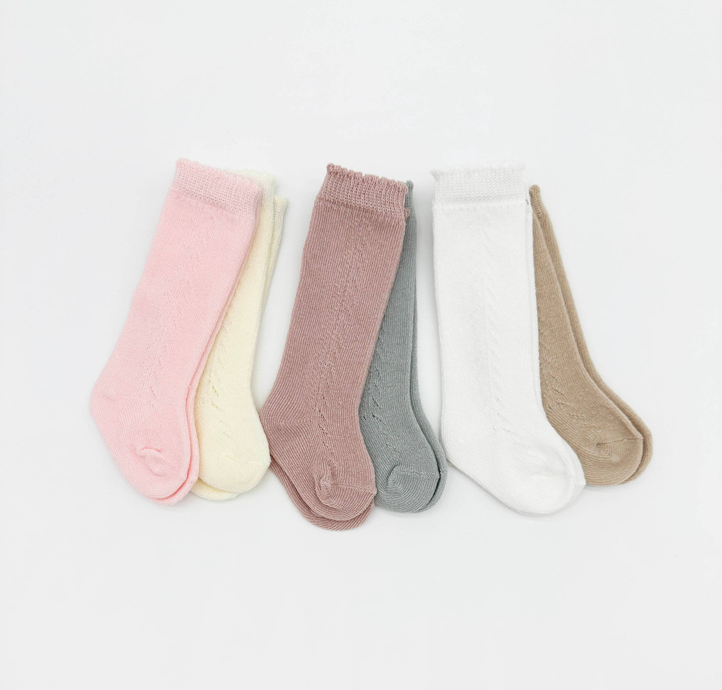Set of five pairs of baby socks in various colors on a light gray background