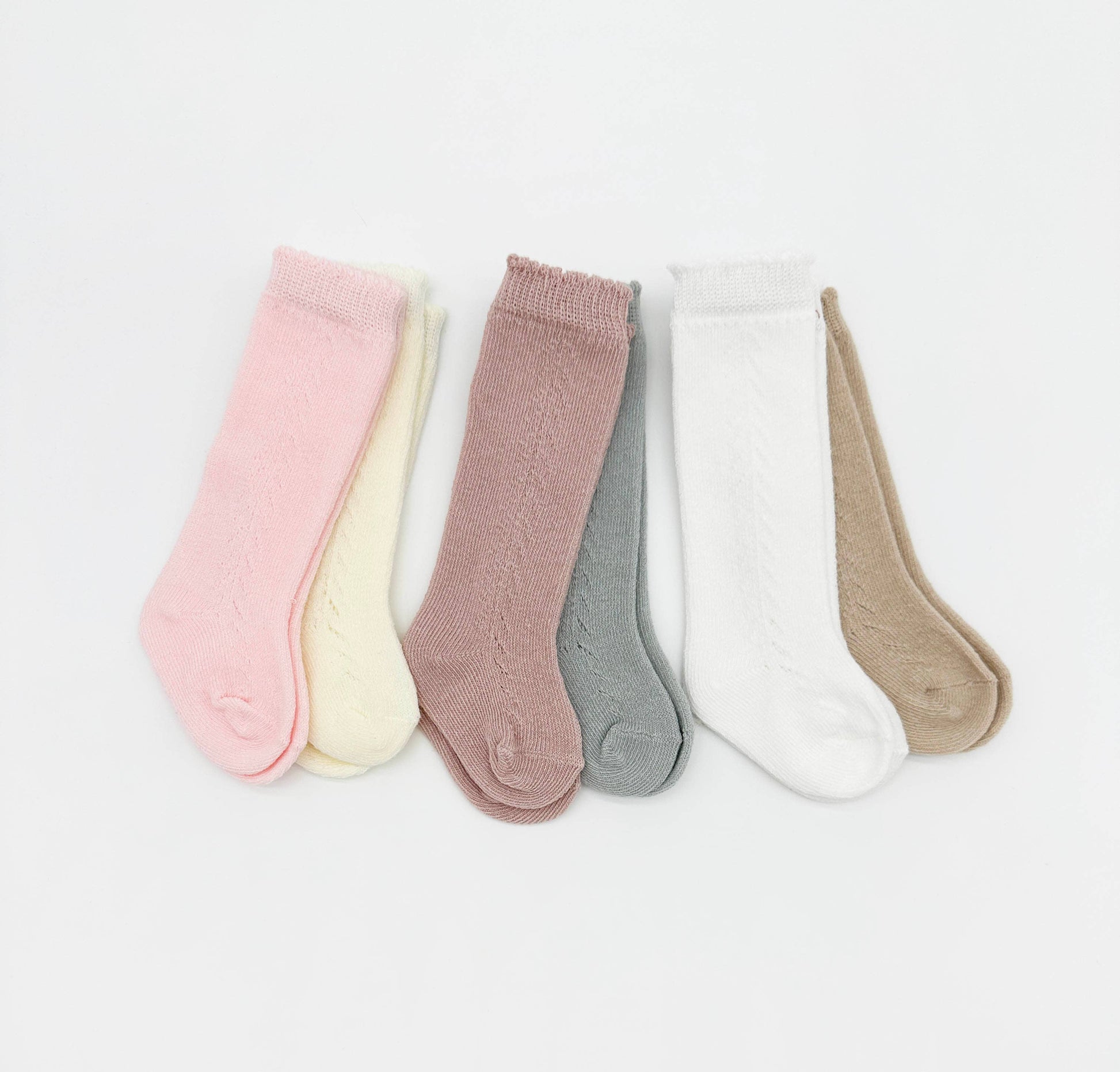 Set of five pairs of baby socks in various colors on a light gray background