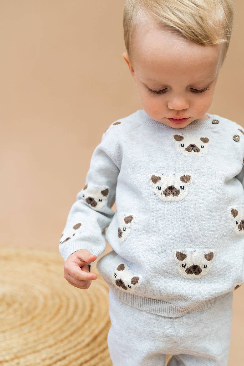 Child wearing a light gray sweater with bear designs on a beige background