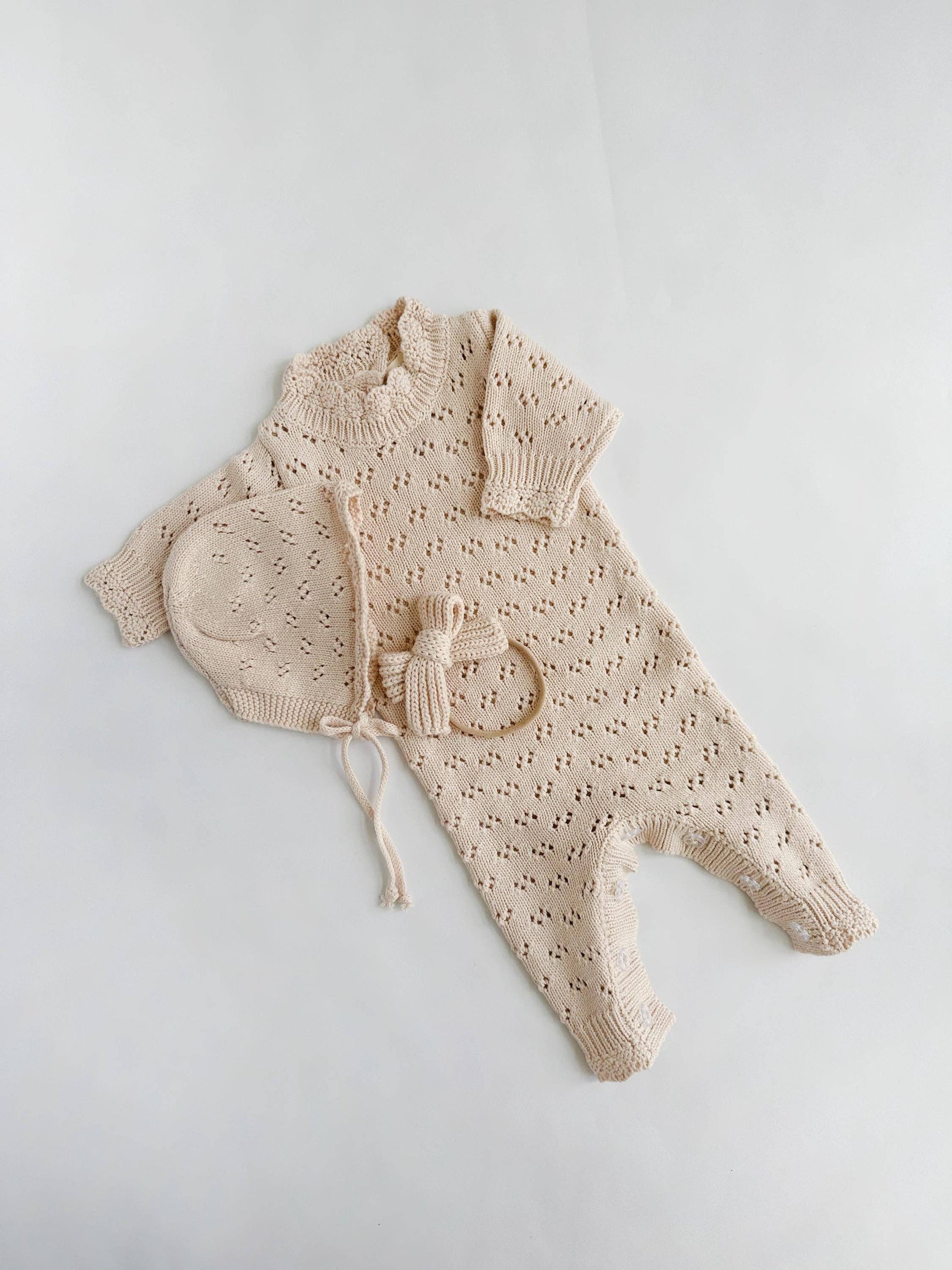 Beige baby outfit with a hat on a light gray background