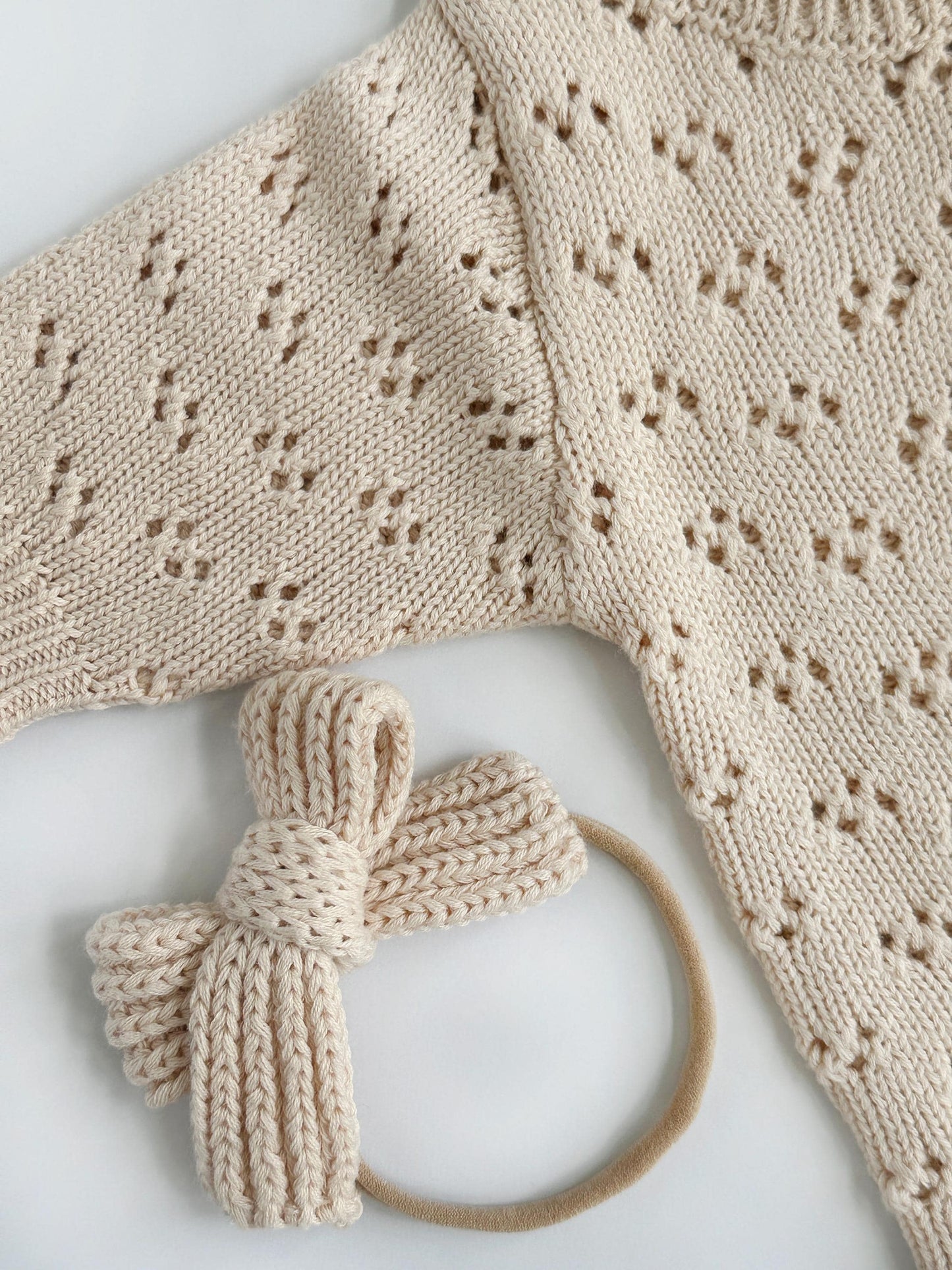 Knitted baby outfit with a headband on a light background