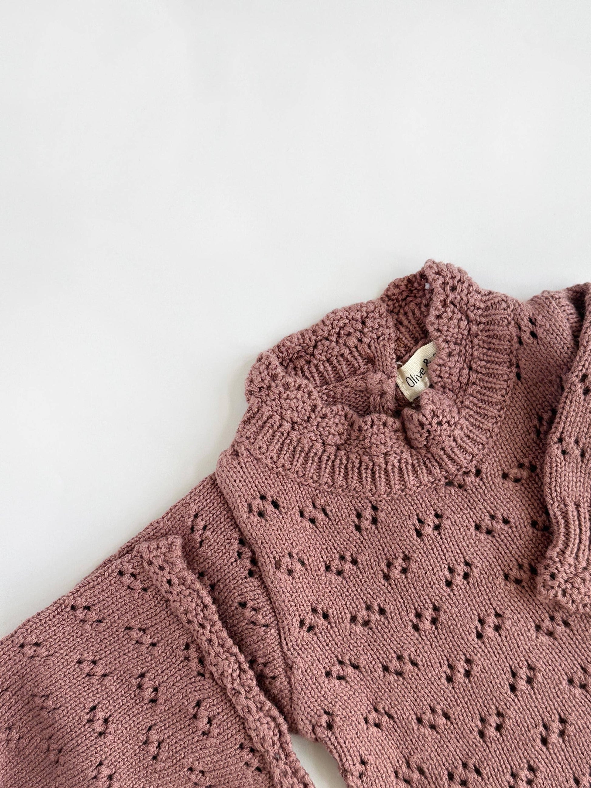 Pink knitted sweater with a textured pattern on a white background