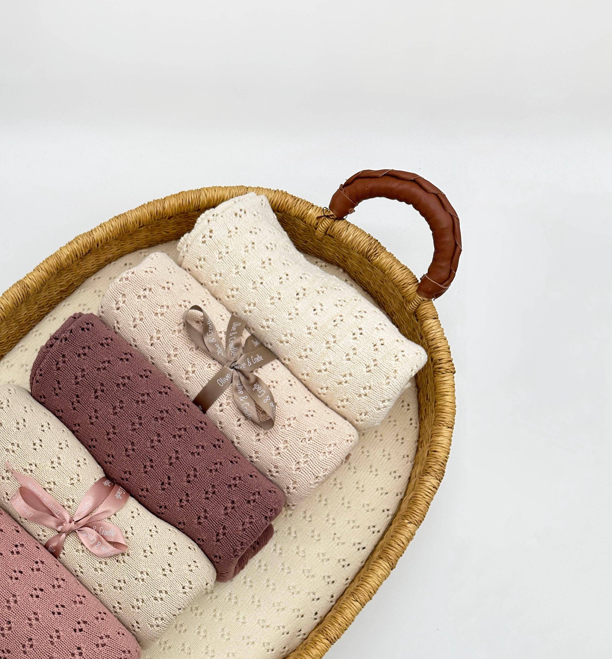 Woven basket with baby blankets in various colors on a white background