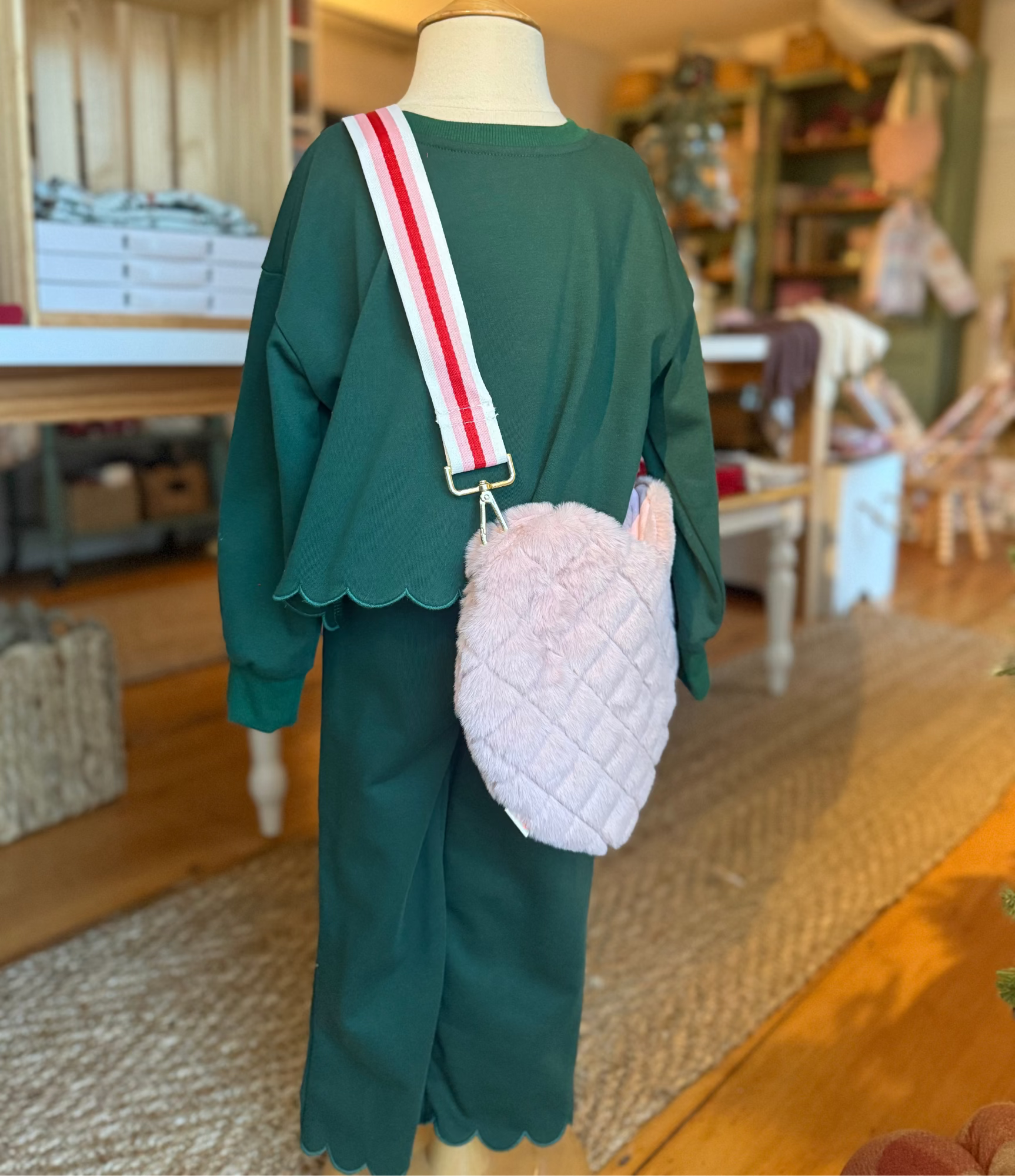 Mannequin wearing a green outfit with a pink quilted bag in a store setting