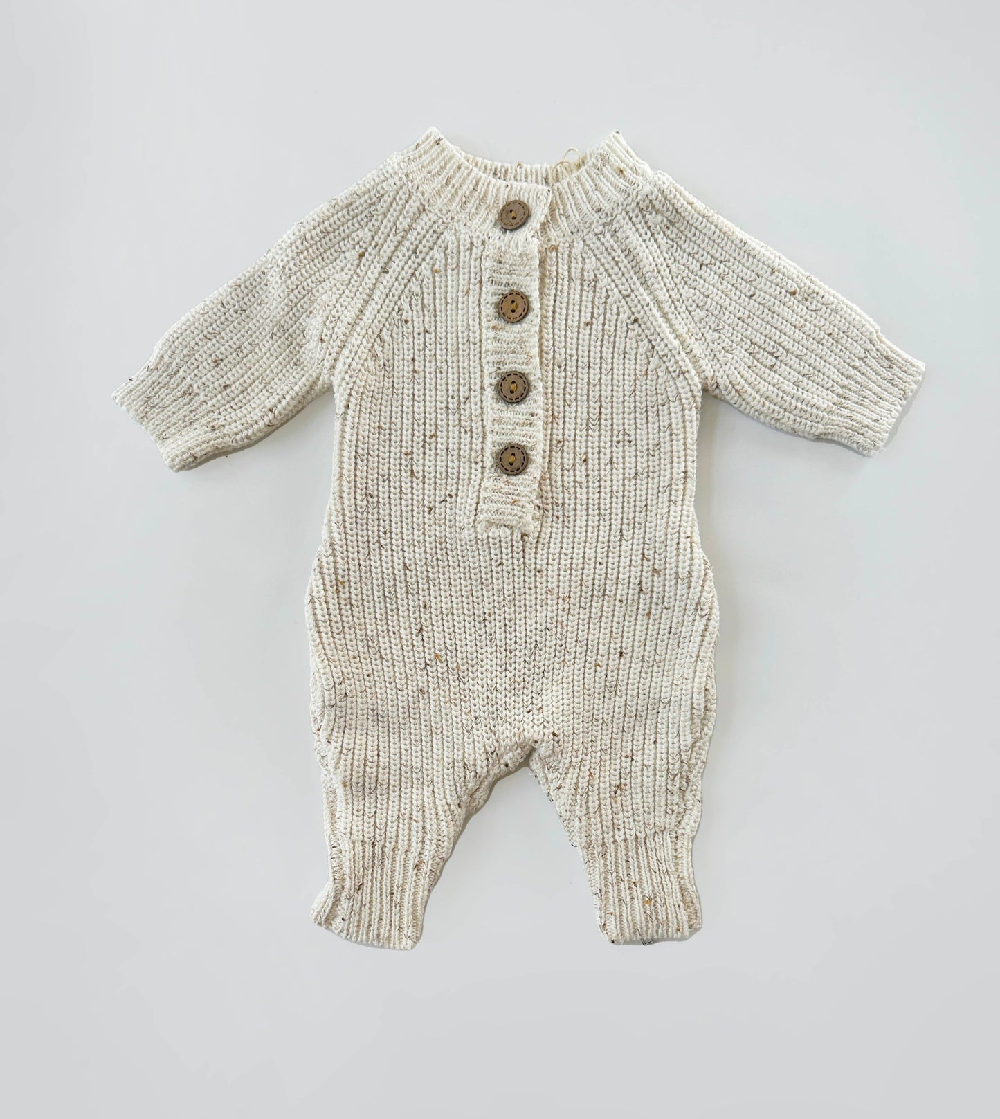 Knitted baby romper with buttons on a light gray background
