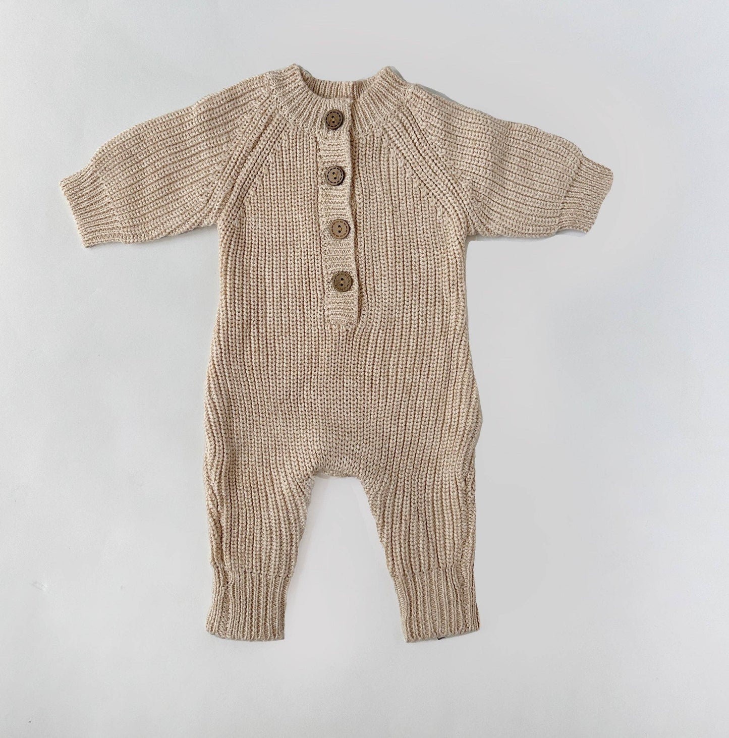 Knitted baby romper with buttons on a light gray background