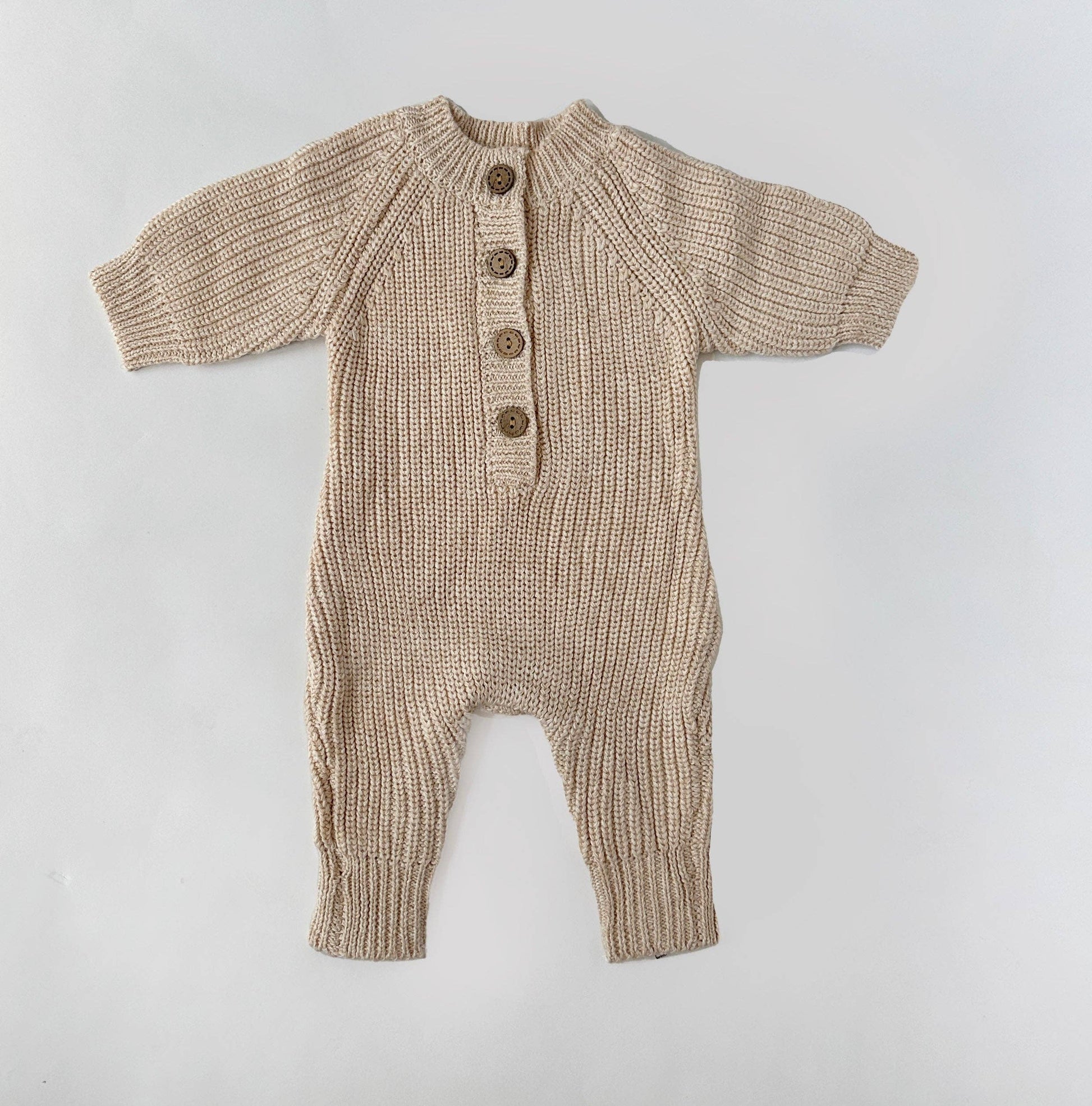 Knitted baby romper with buttons on a light gray background