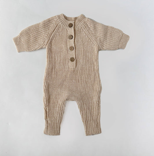 Knitted baby romper with buttons on a light gray background
