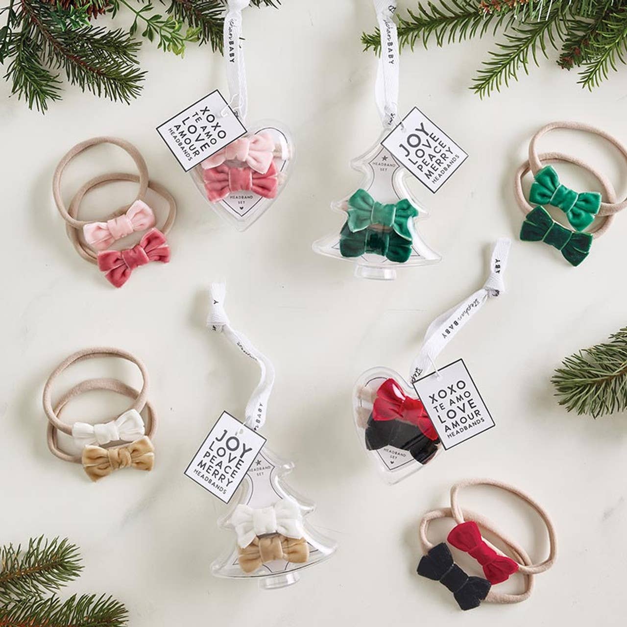 Decorative hair bow sets in clear glass ornaments with Christmas tree branches.