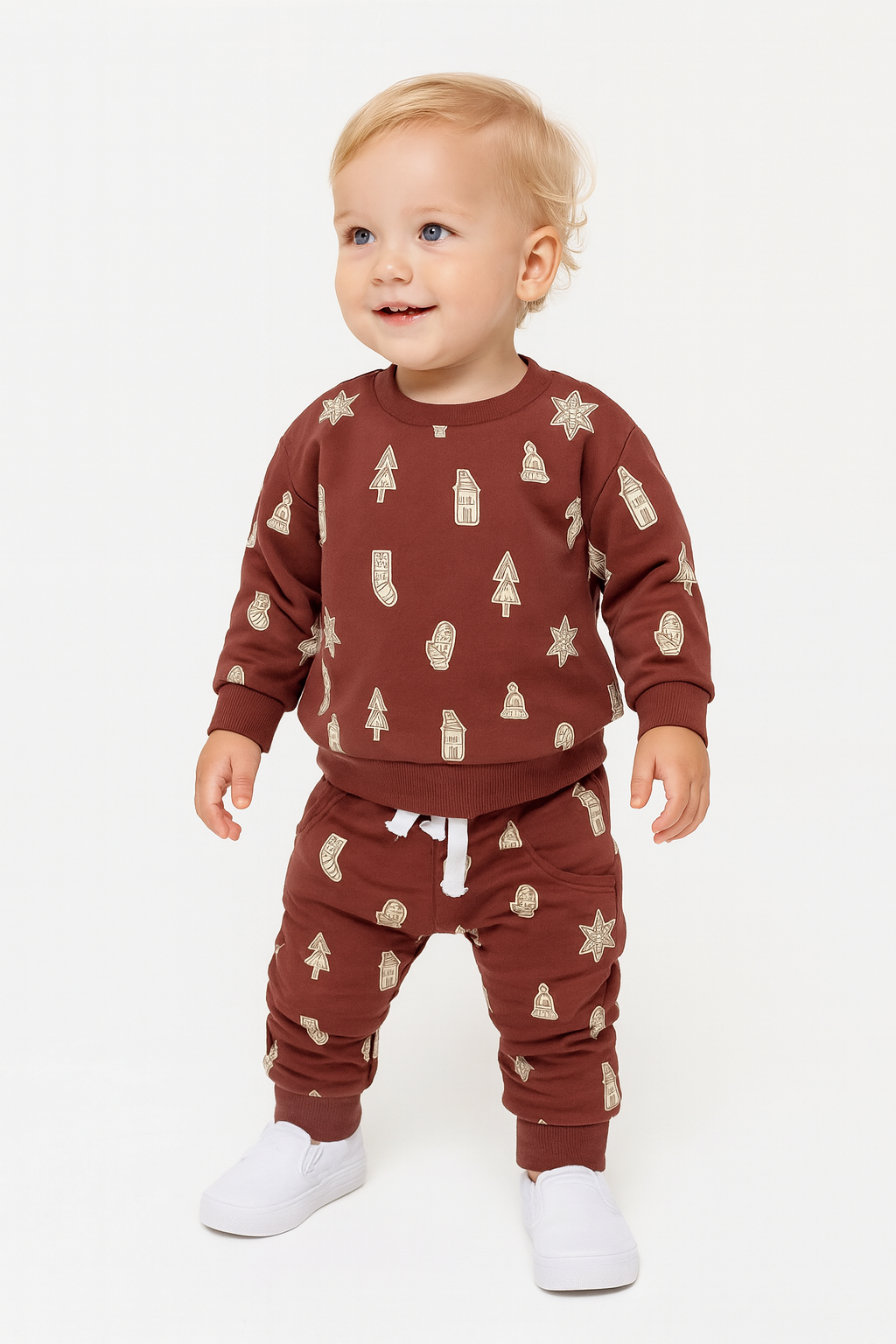 Baby wearing a brown outfit with tree pattern on a white background