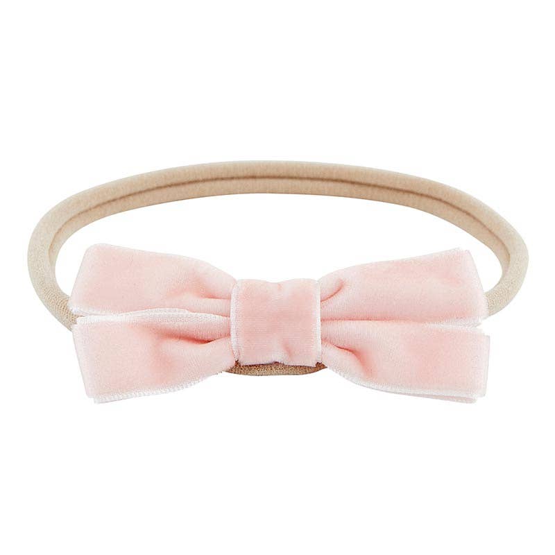 Pink velvet bow headband on a white background