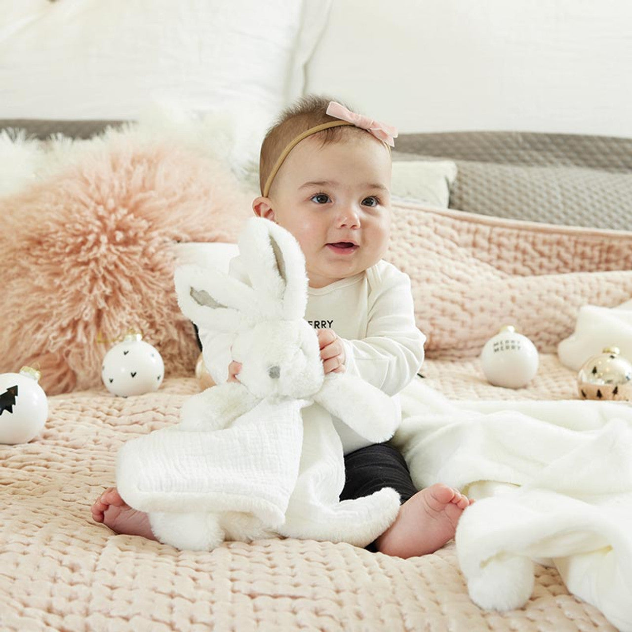 Baby holding a plush toy in a cozy indoor setting with soft lighting