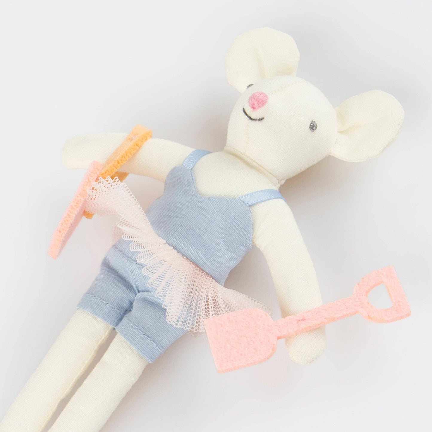 Stuffed toy mouse in a blue outfit with a pink shovel on a light gray background