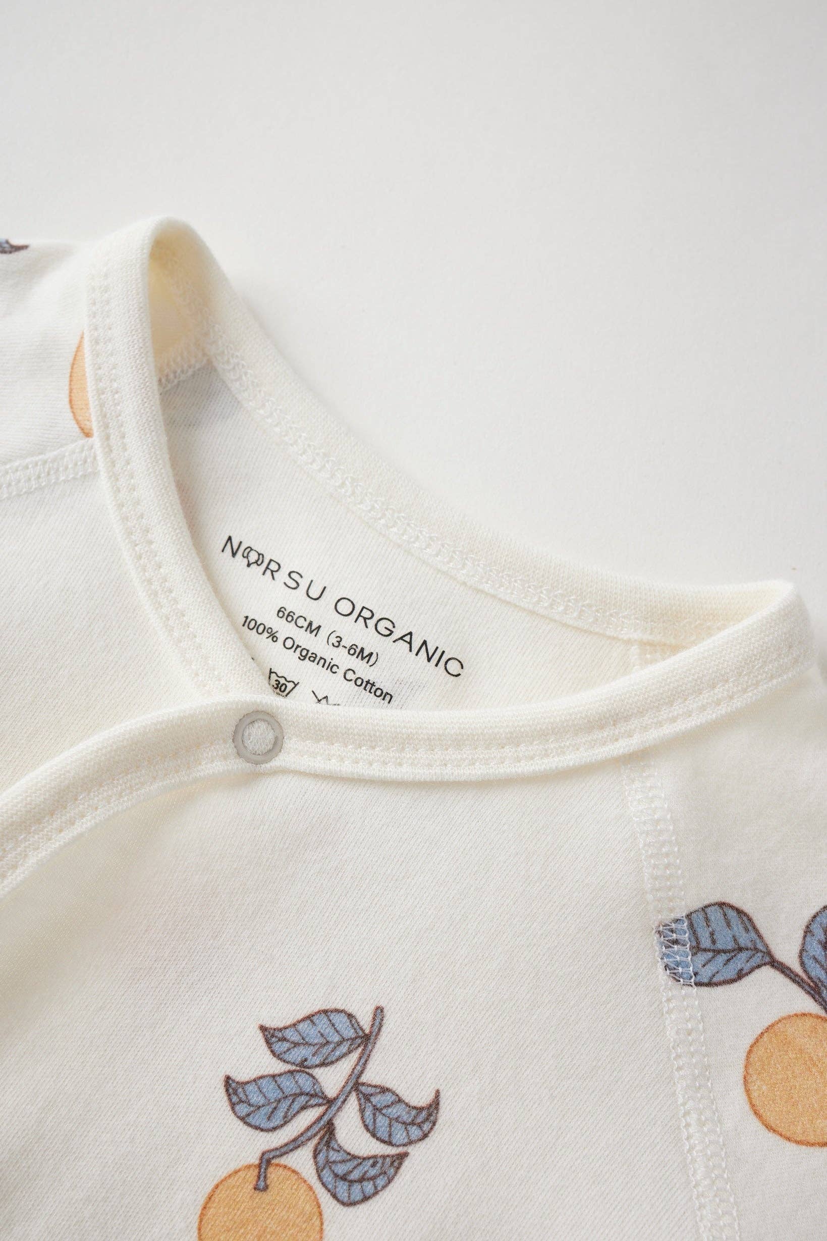 Close-up of a baby outfit with 'NORSU ORGANIC' label on a white background
