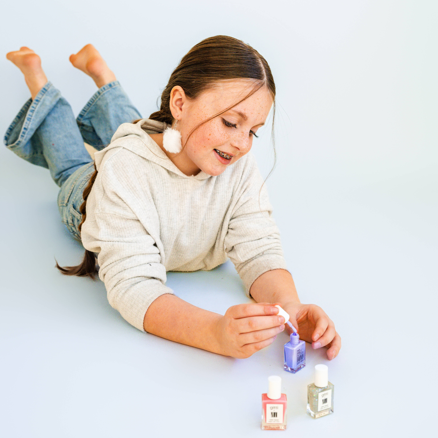 Child playing with nail polish bottles on a light blue background