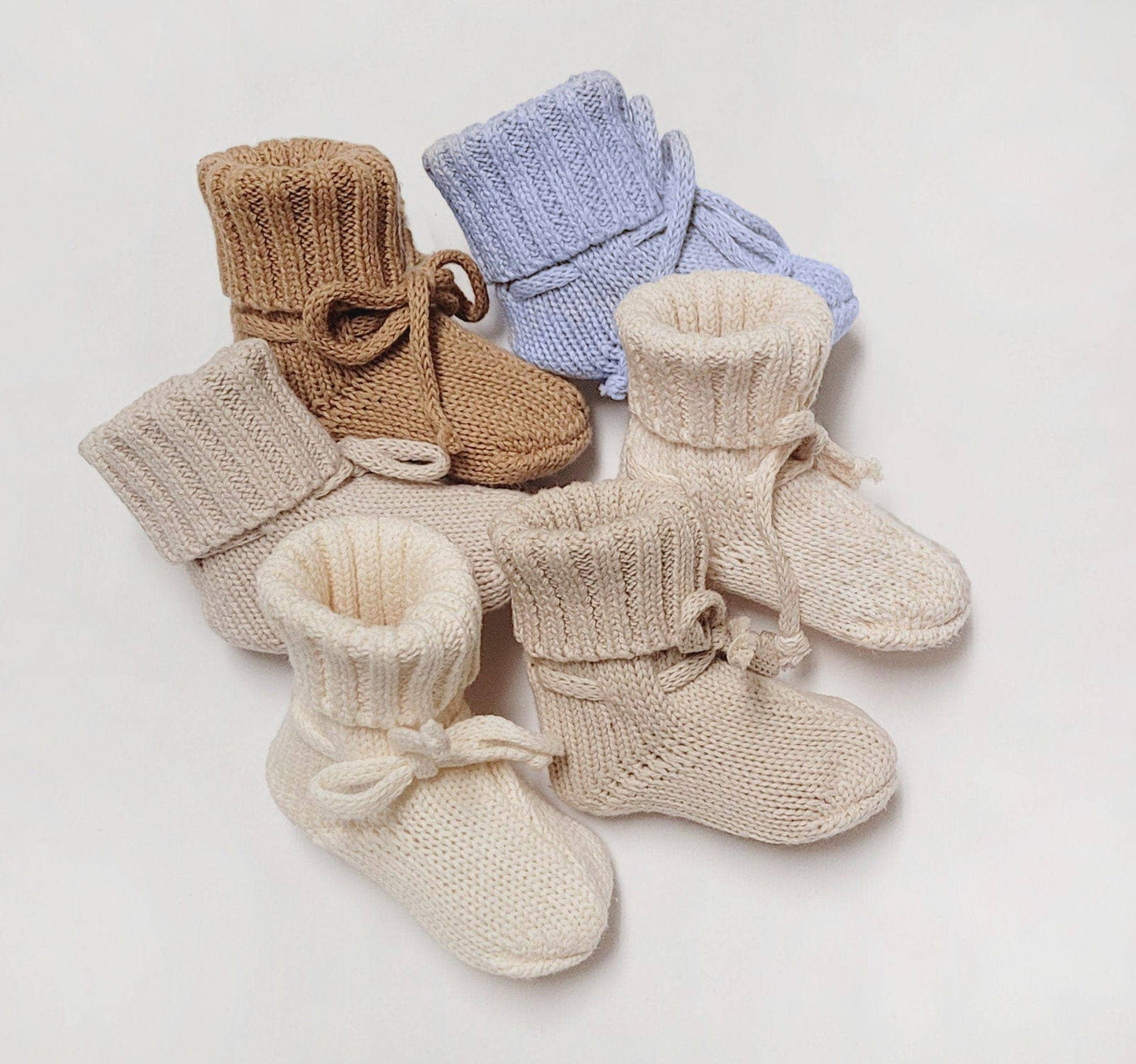 Set of knitted baby boots in various colors on a light background