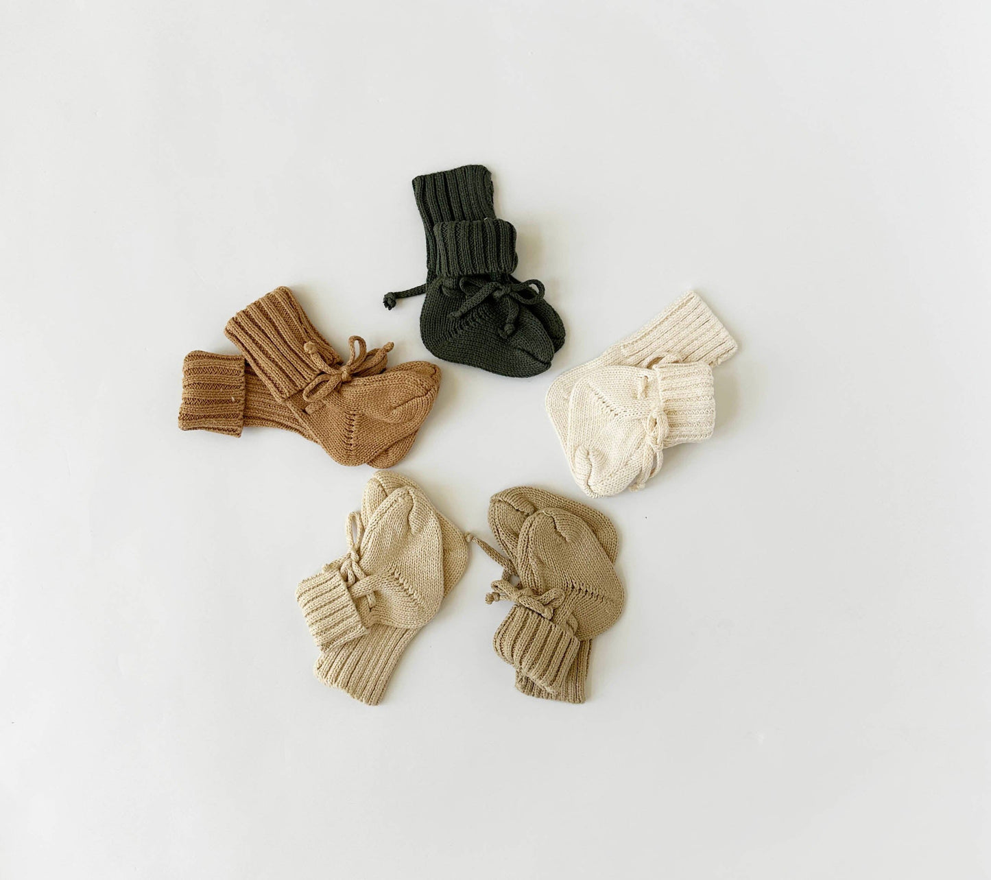 Set of baby booties in brown, beige, and black on a light gray background
