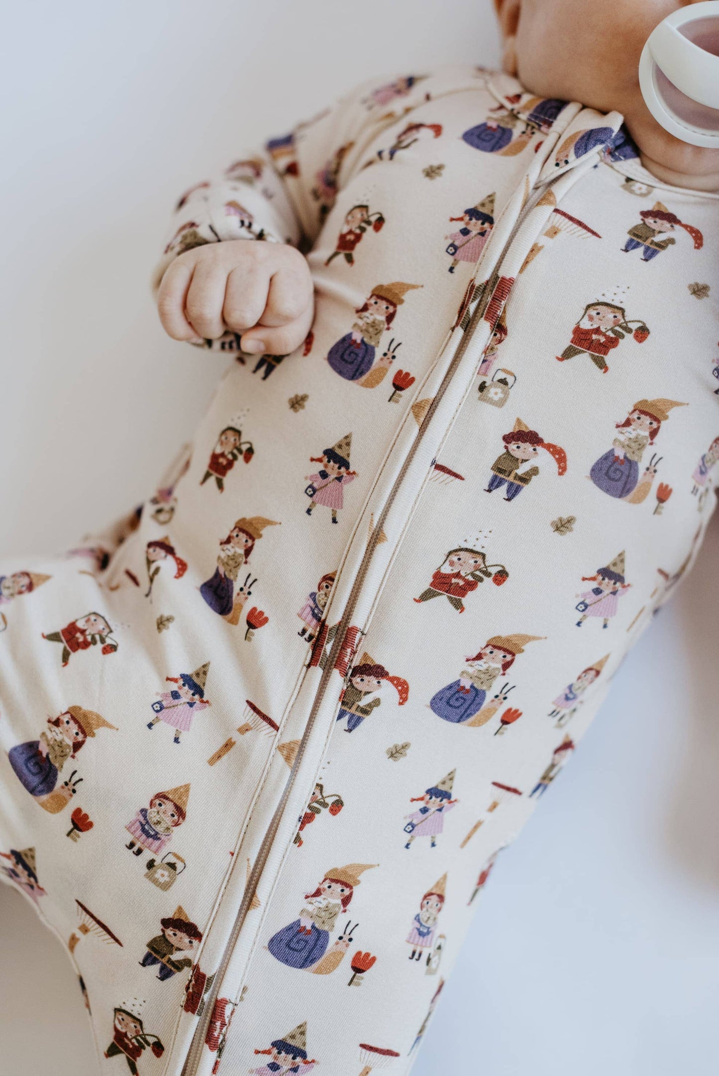 Baby in a patterned sleeping bag on a white background