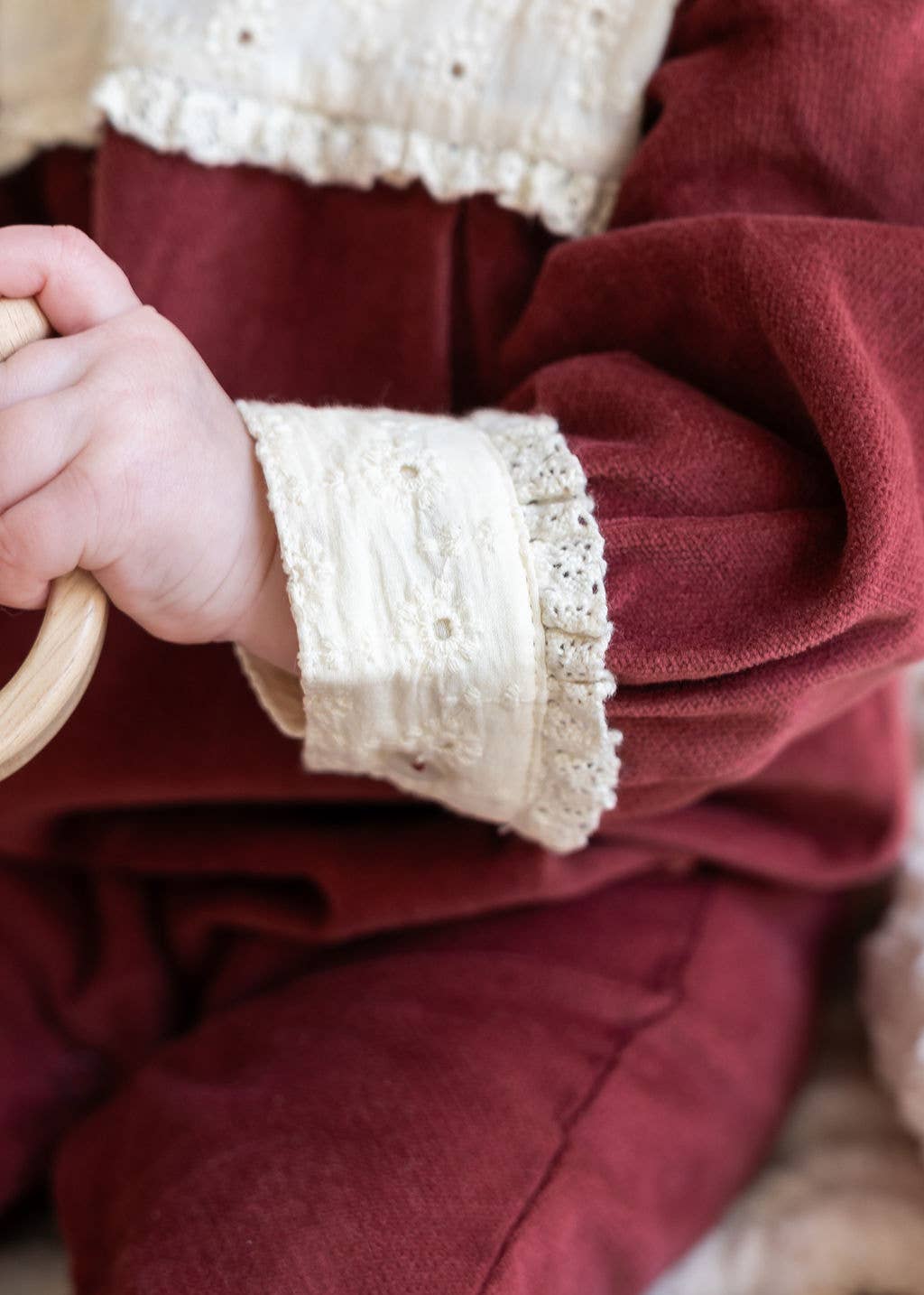 Close-up of a person wearing a burgundy garment with lace cuffs.
