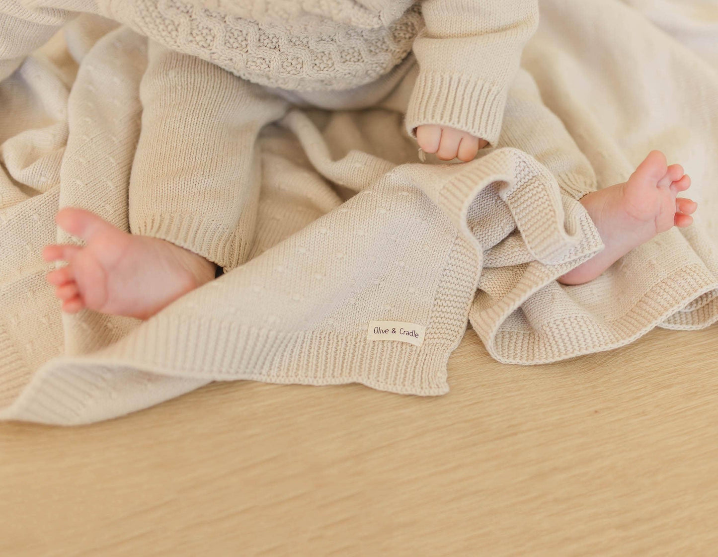 Baby's feet in beige knitted pants with a soft blanket