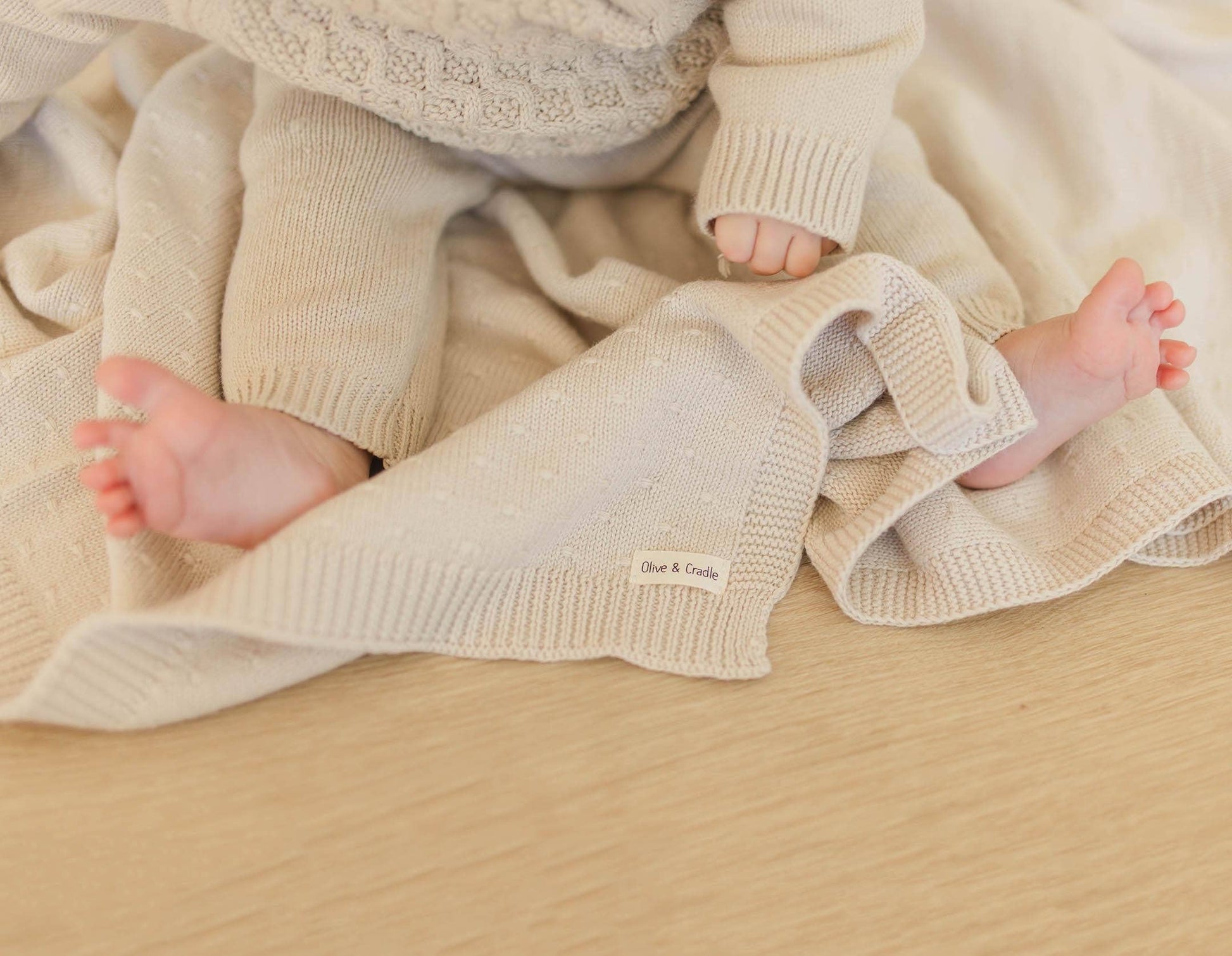 Baby's feet in beige knitted pants with a soft blanket