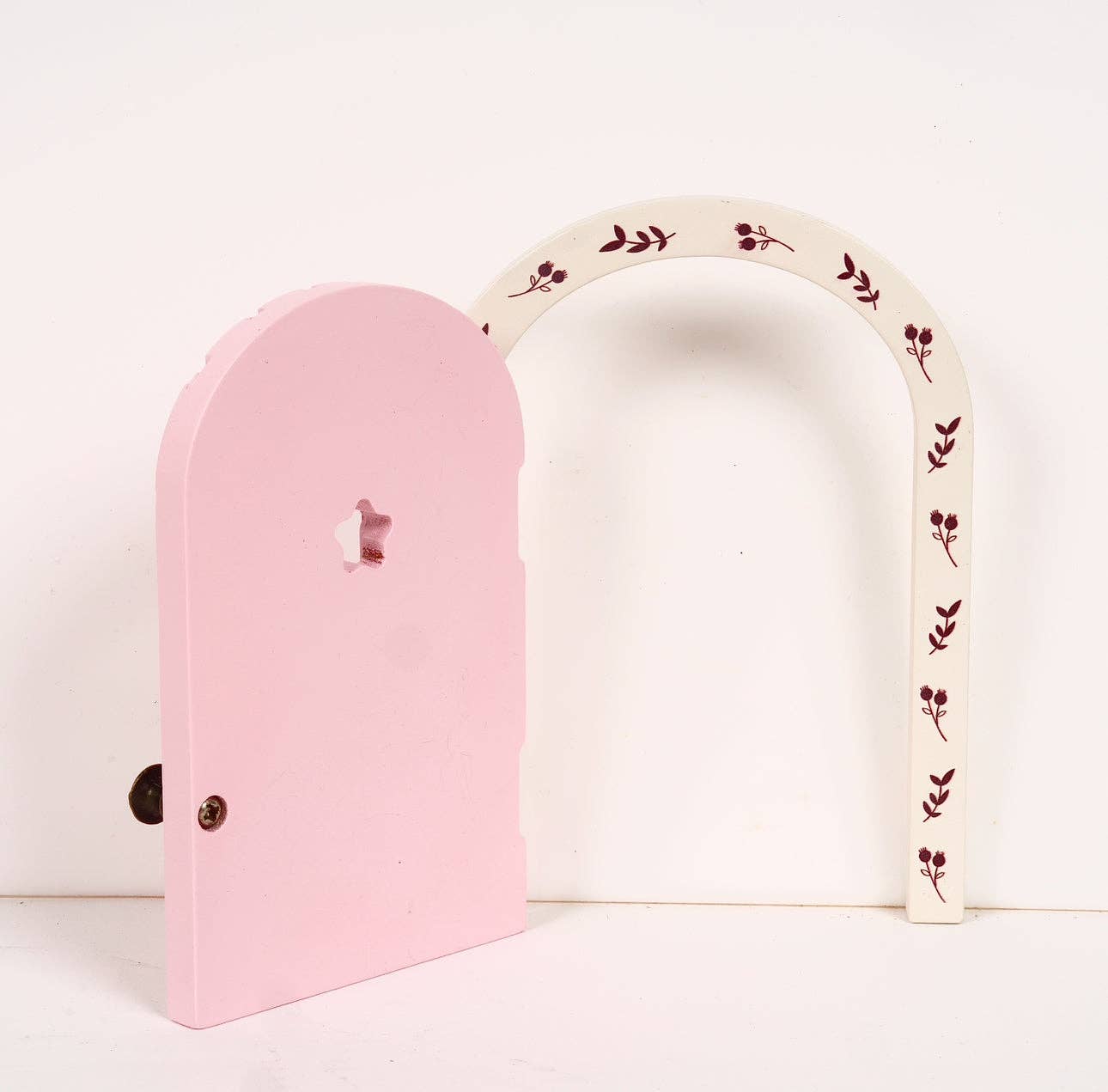 Pink and white fairy doors with decorative elements on a light background
