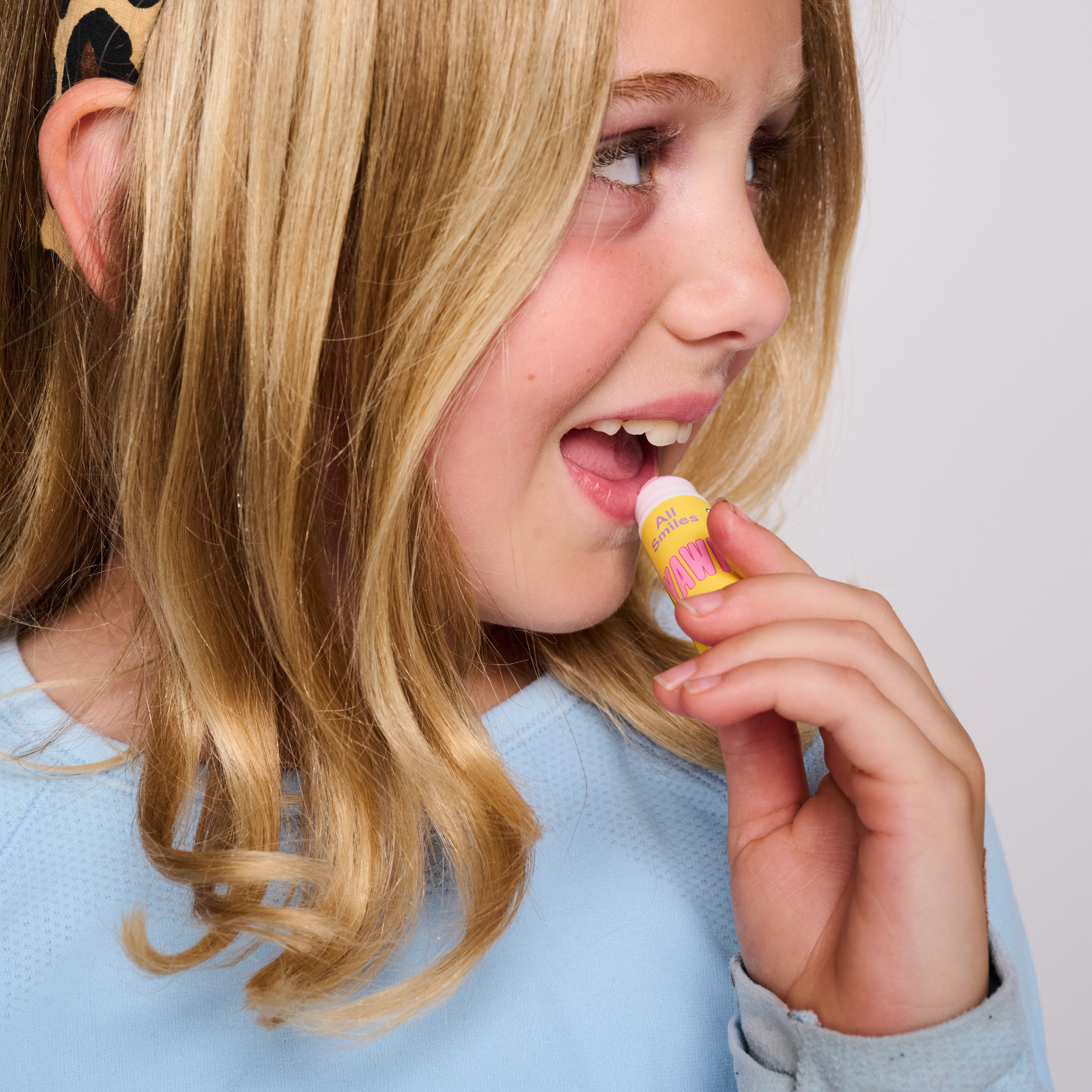 Young girl applying lip balm with a white background