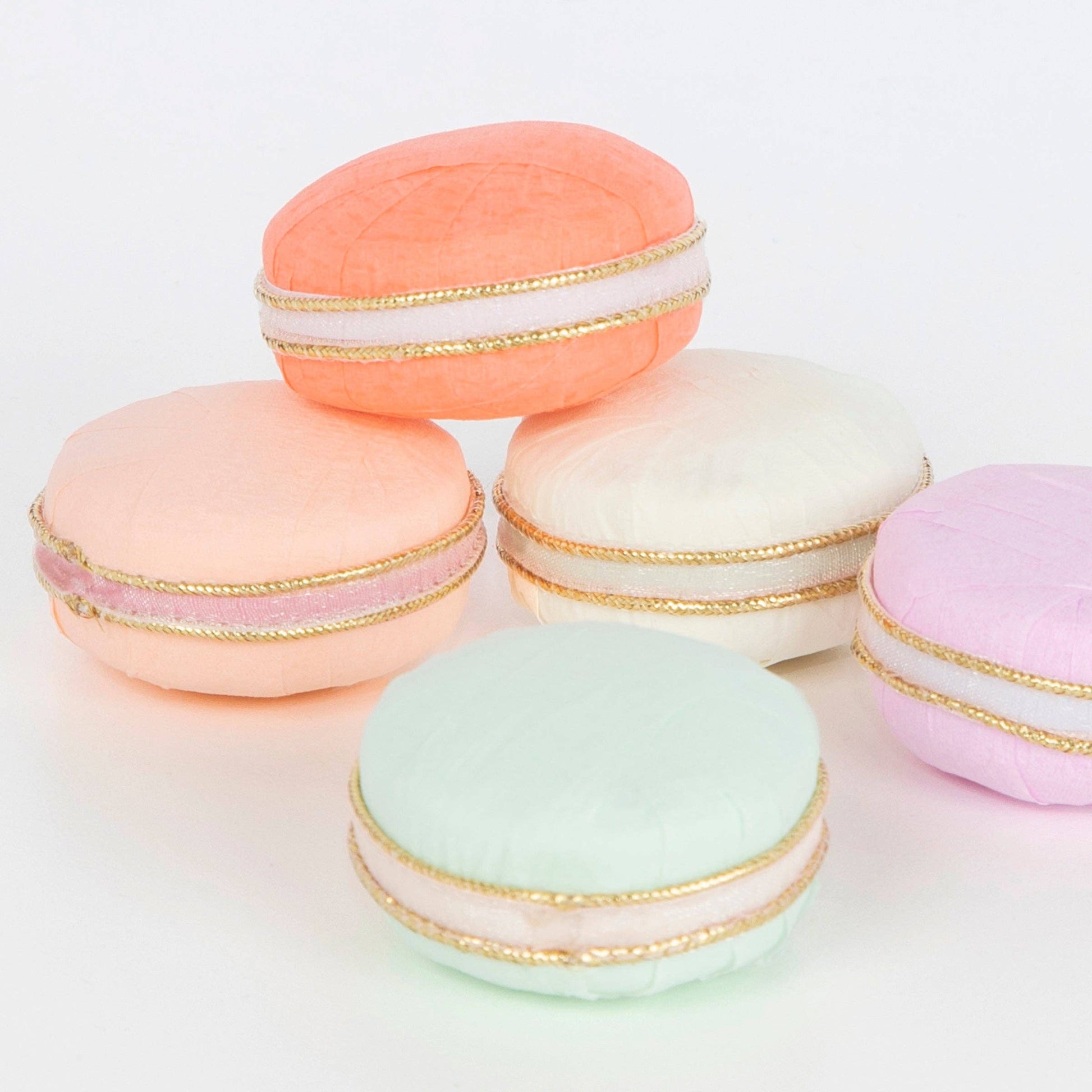 Pastel-colored macarons with gold accents on a white background