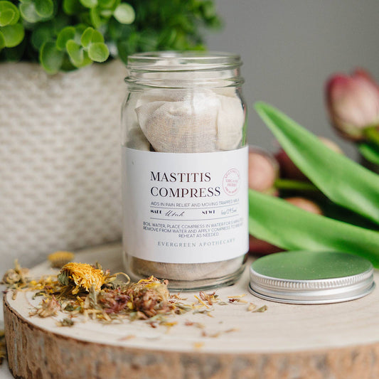 Jar labeled 'Mastitis Compress' on a wooden surface with plants in the background