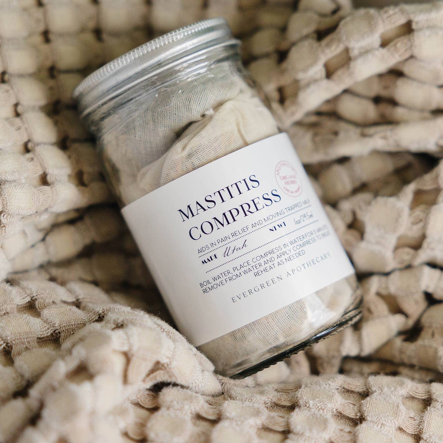 Jar of Mastitis Compresses on a woven surface