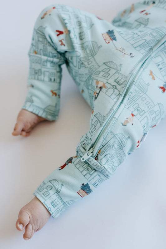 Baby's foot wearing a light blue patterned onesie on a white background