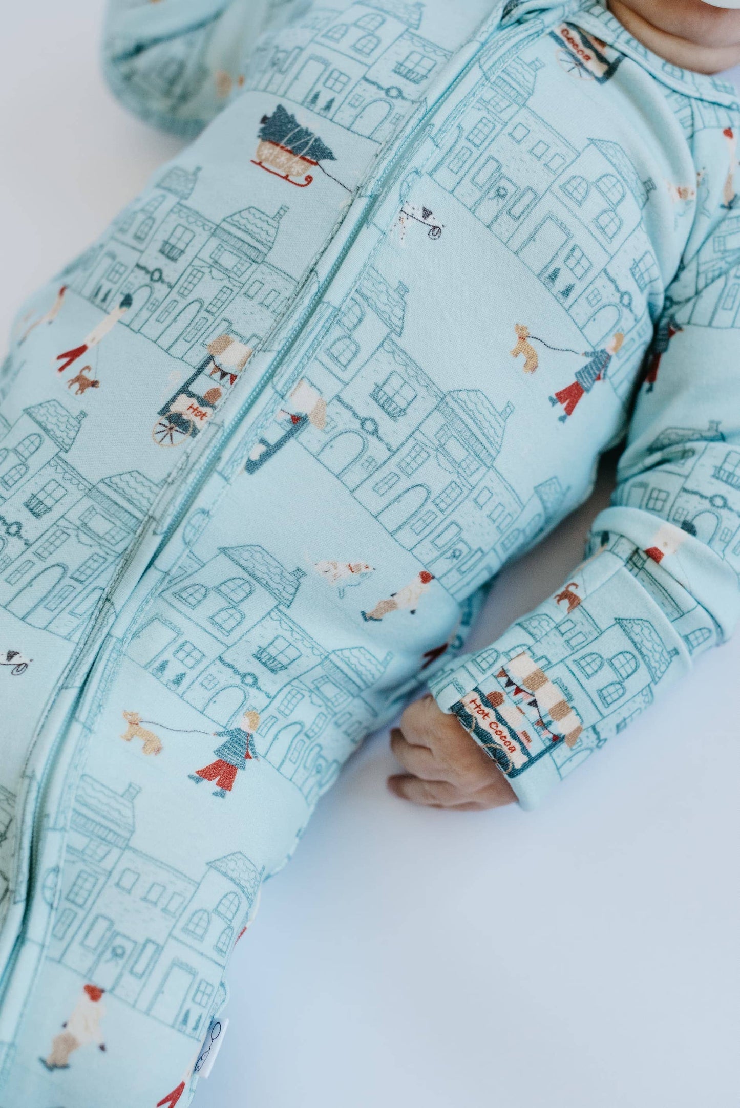 Baby wearing a light blue onesie with a cityscape pattern on a white background
