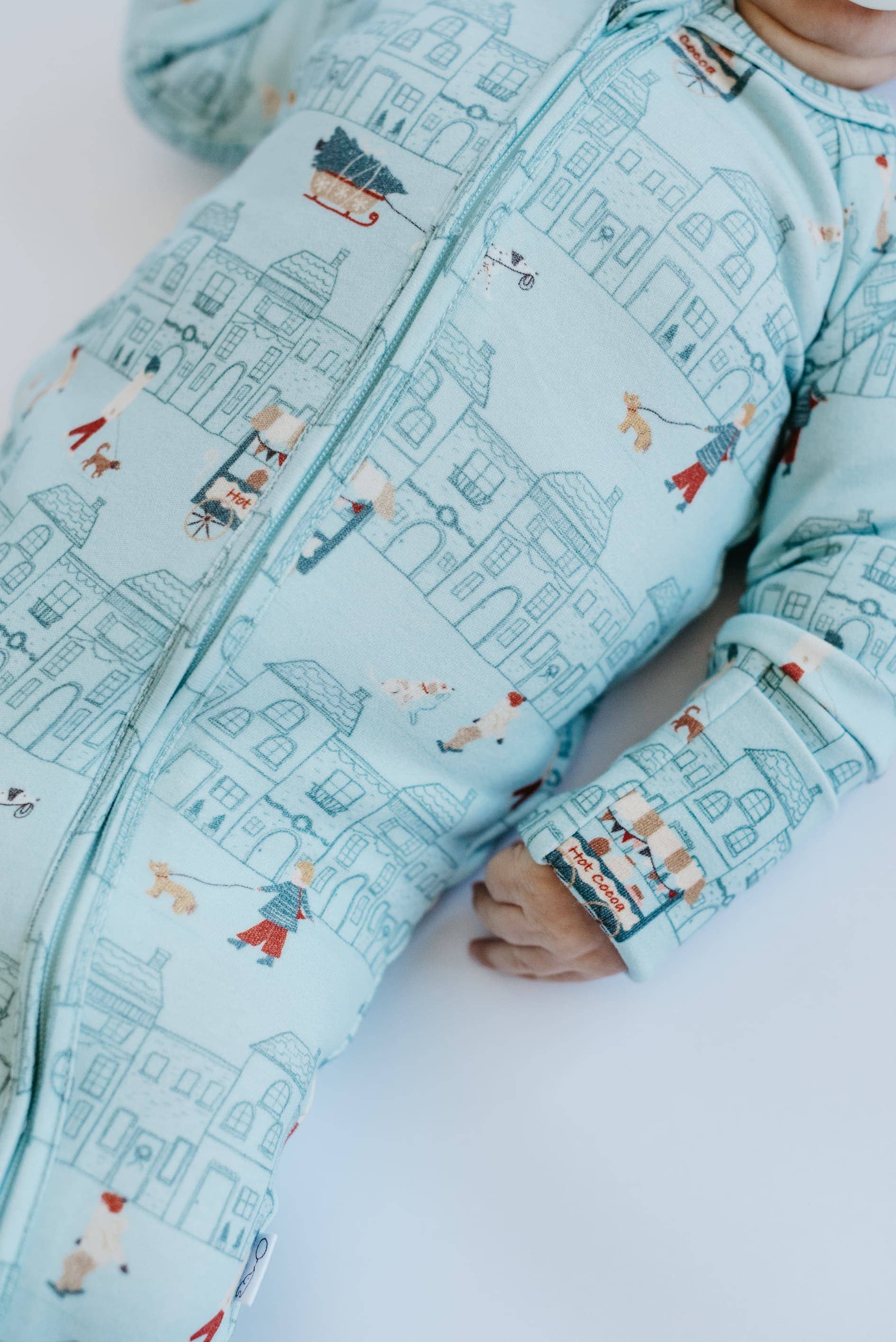 Baby wearing a light blue onesie with a cityscape pattern on a white background