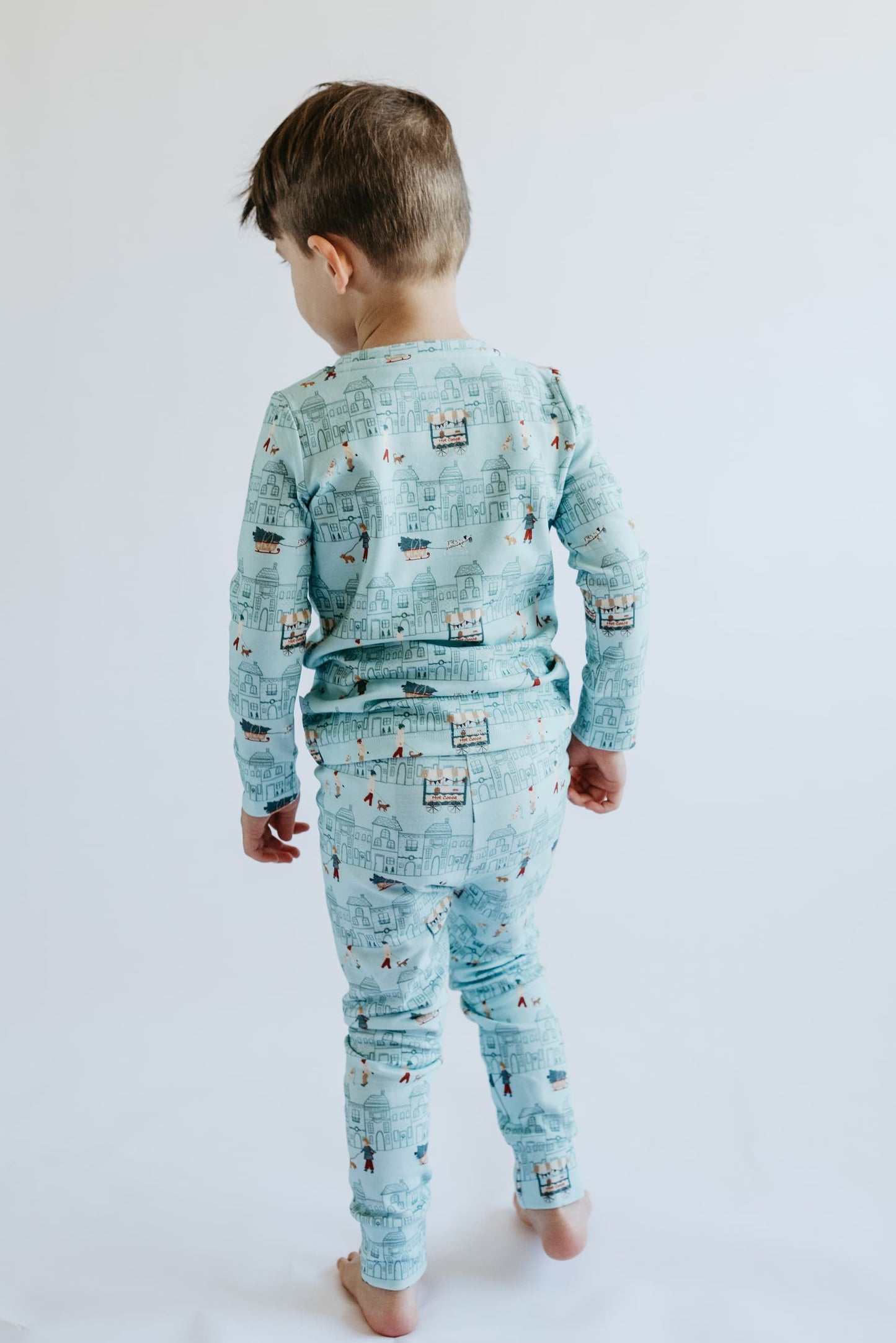 Child wearing a blue pajama set with vehicle pattern on a white background