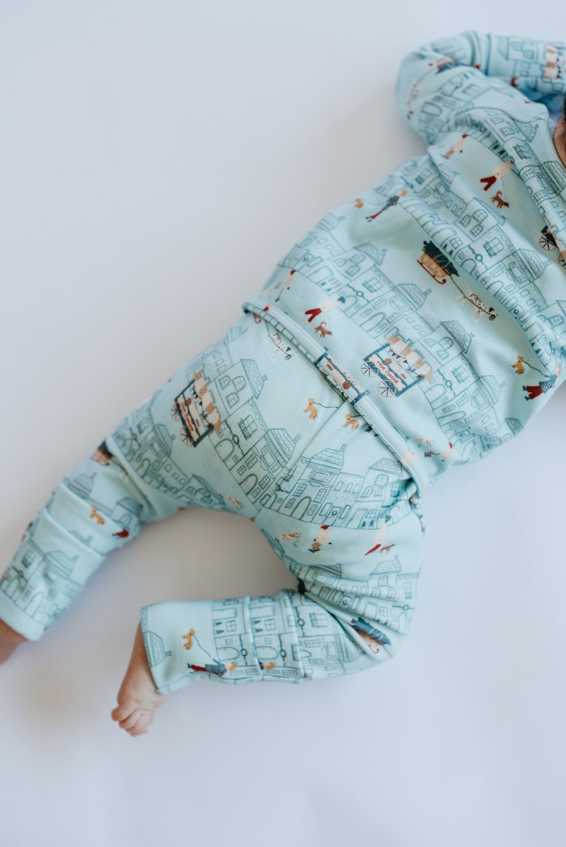 Light blue baby jacket with cityscape pattern on a white background