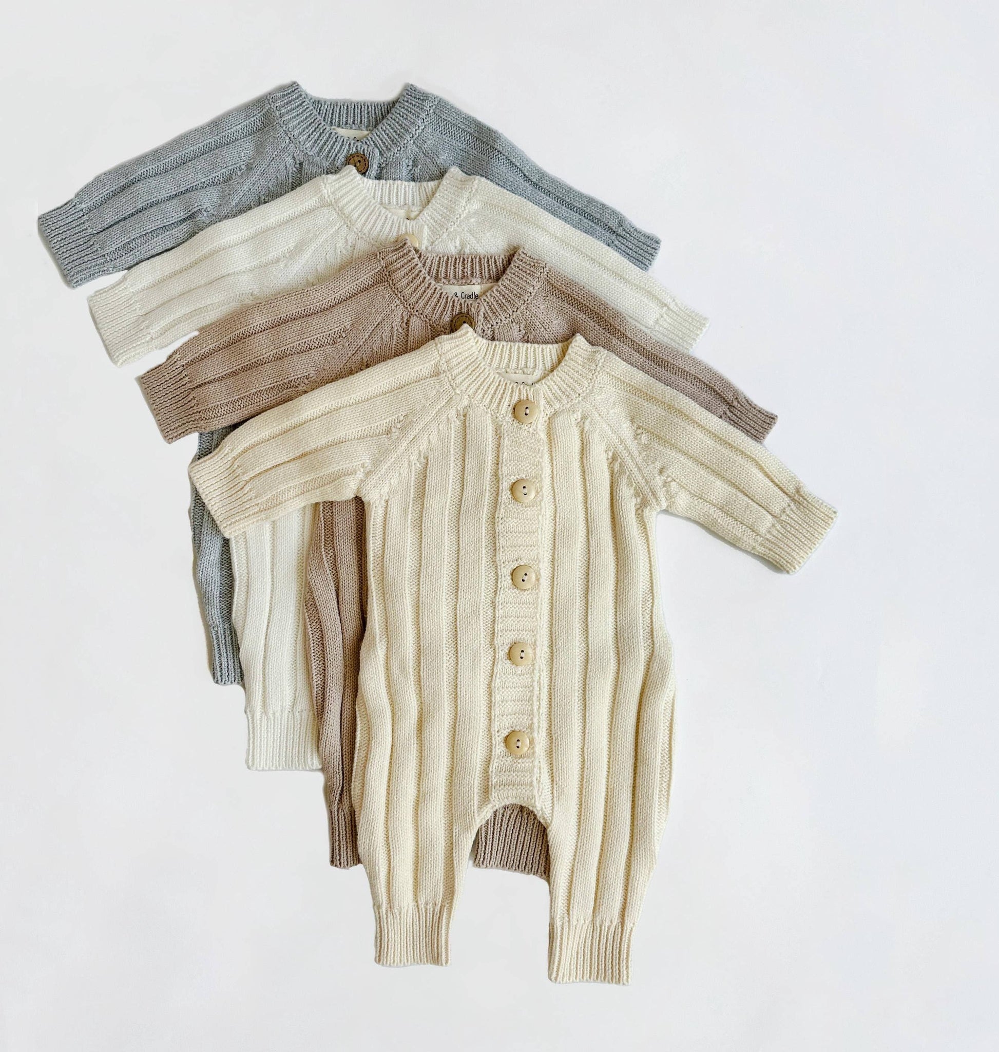 Stack of baby cardigans in various colors on a light background