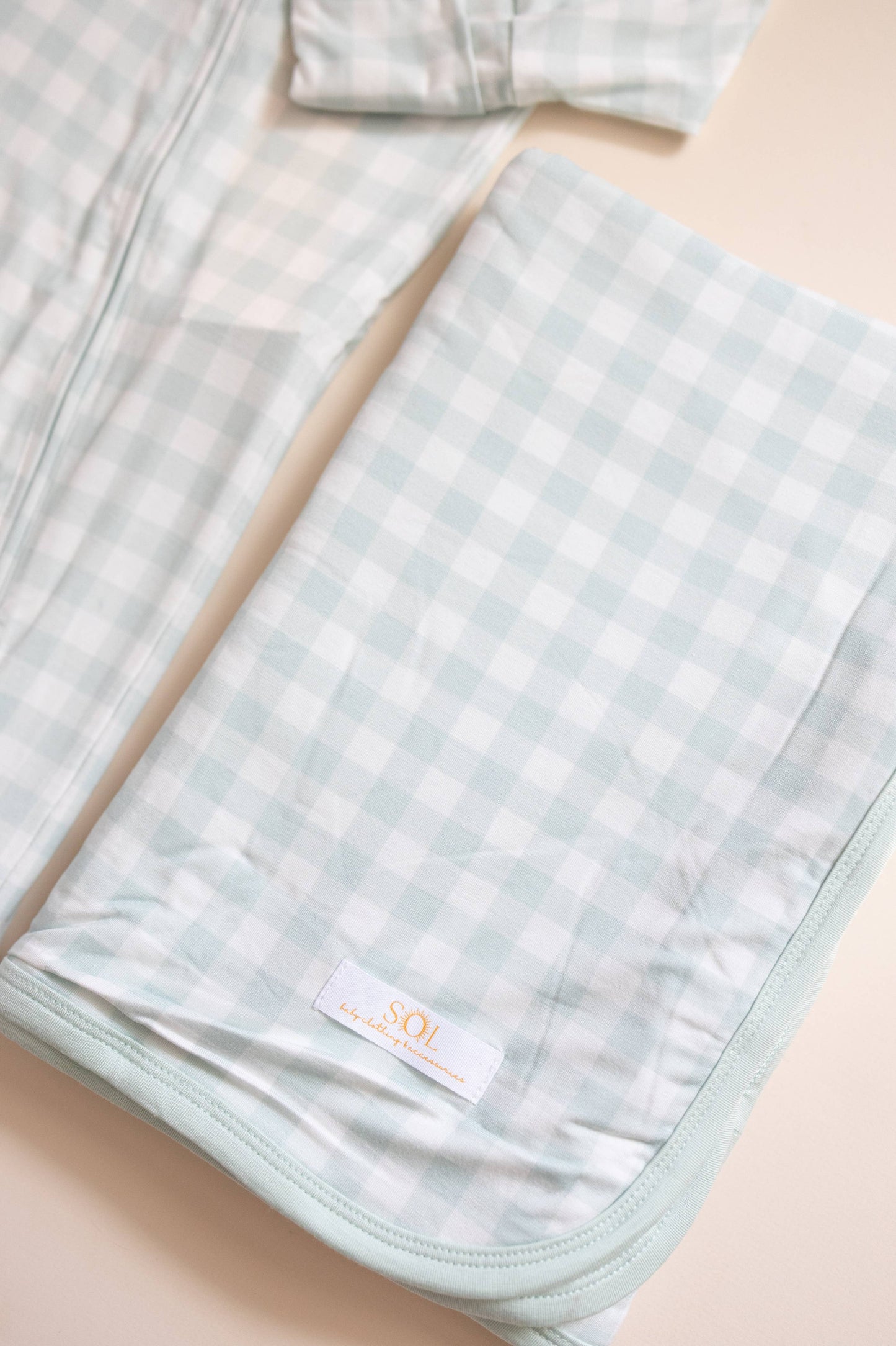 Light blue checkered blanket with a brand label on a beige surface