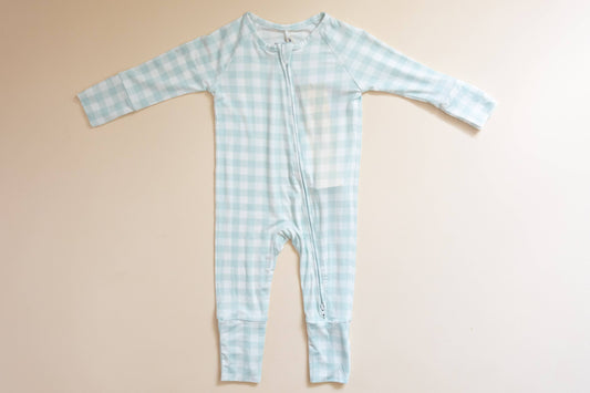 Light blue checkered baby onesie on a beige background