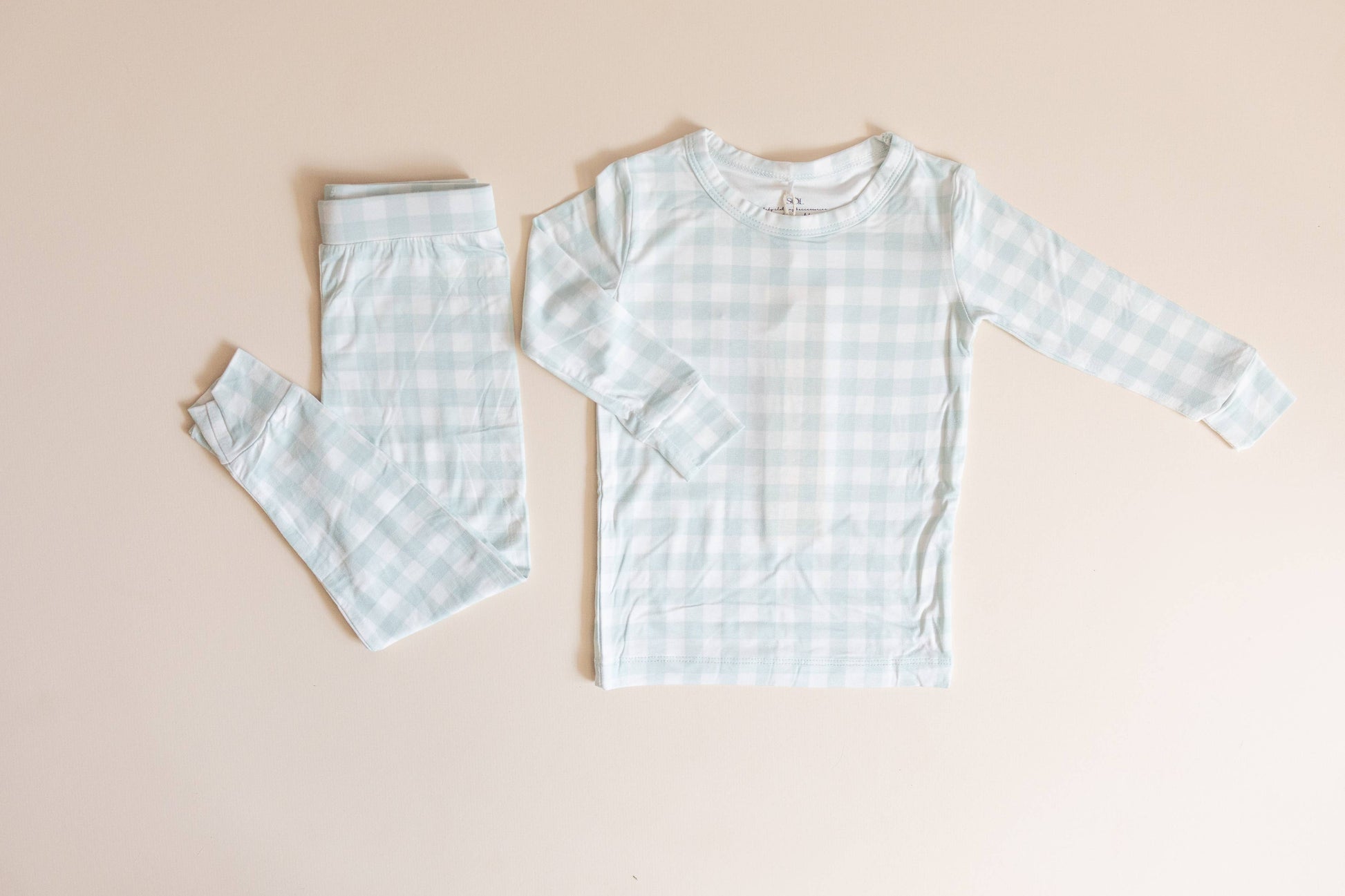 Children's light blue checkered pajama set on a beige background