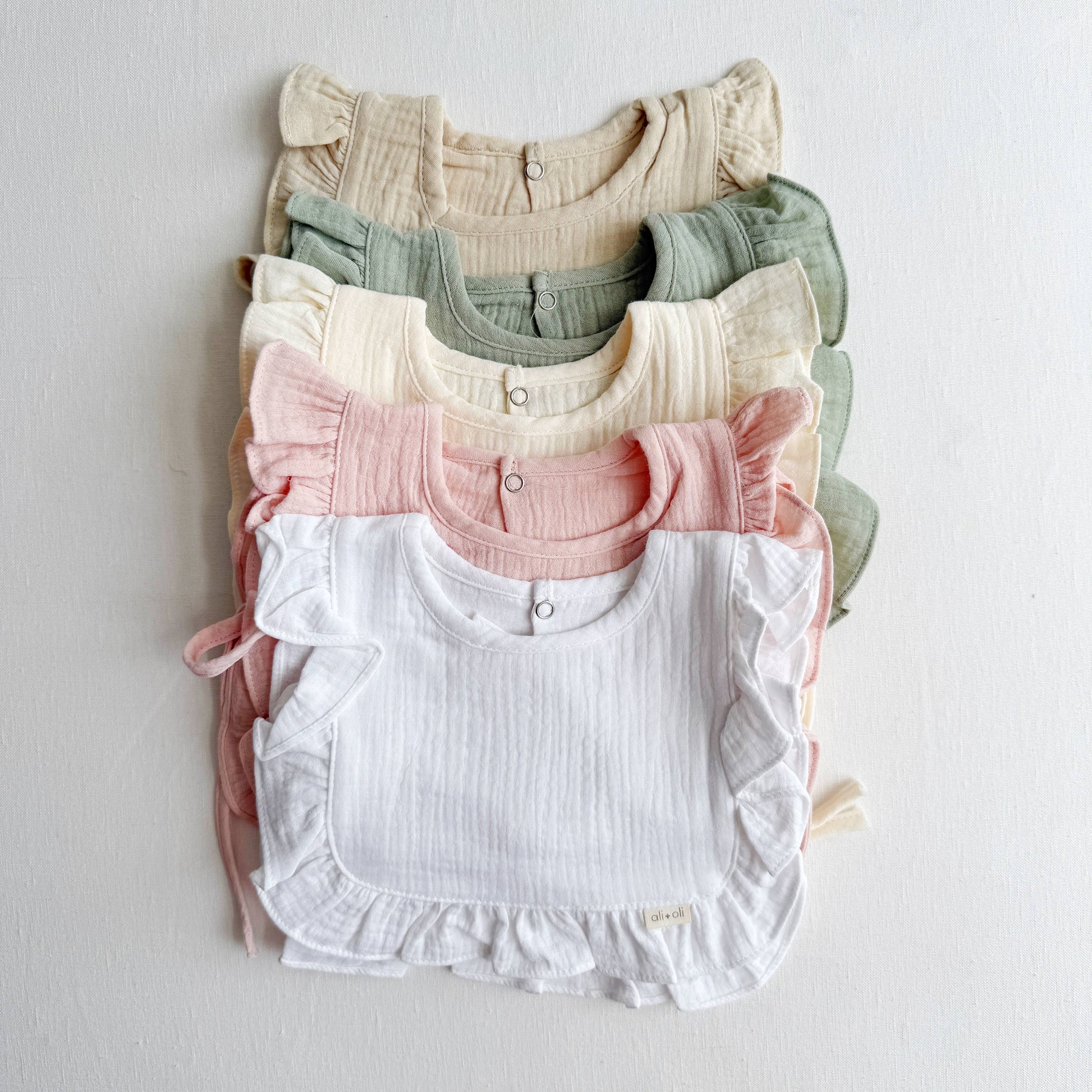 Stack of colorful baby rompers on a light gray background