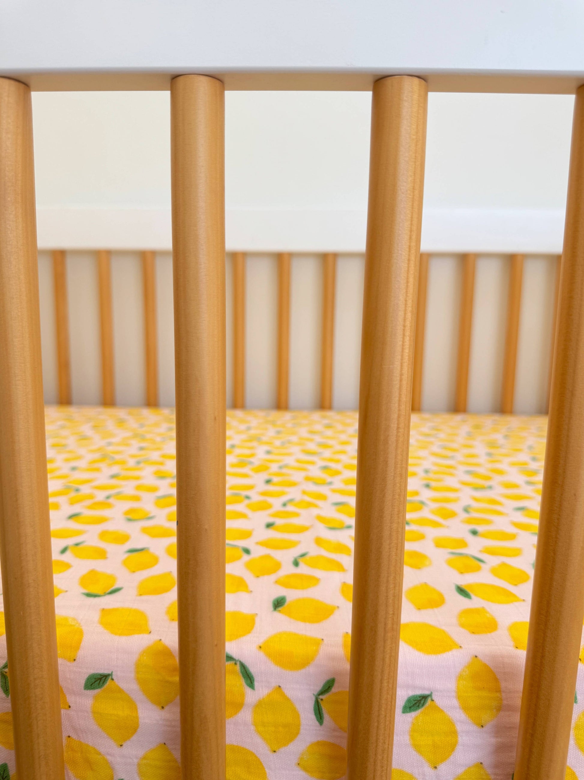 Crib with lemon-patterned sheet and wooden sides