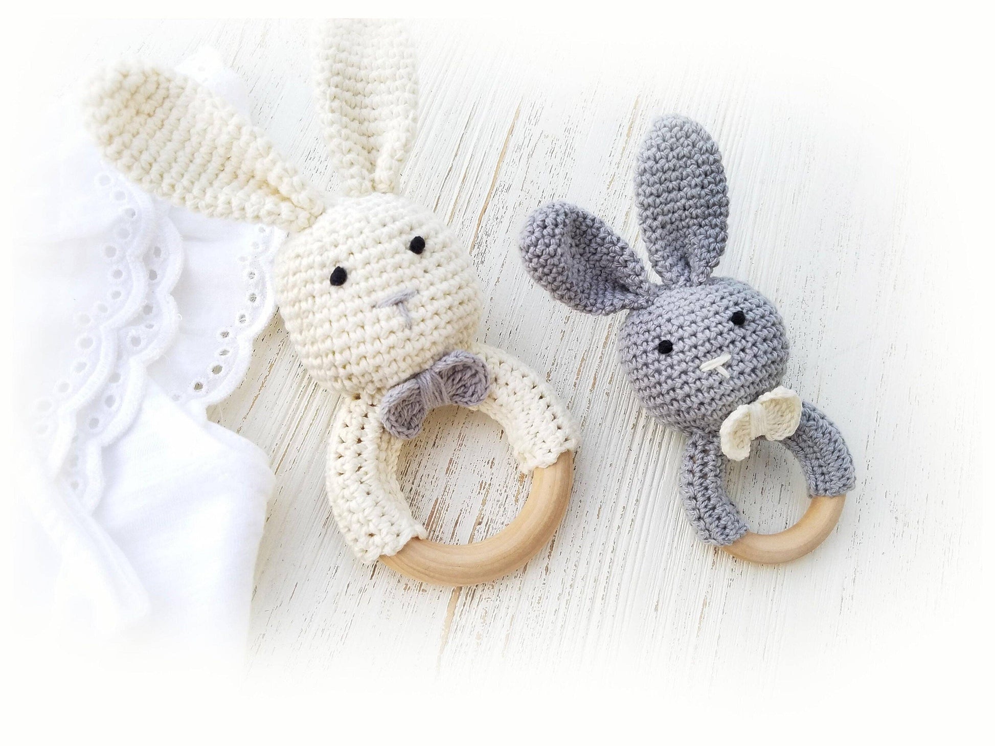 Two crocheted bunny toys with wooden rings on a light background