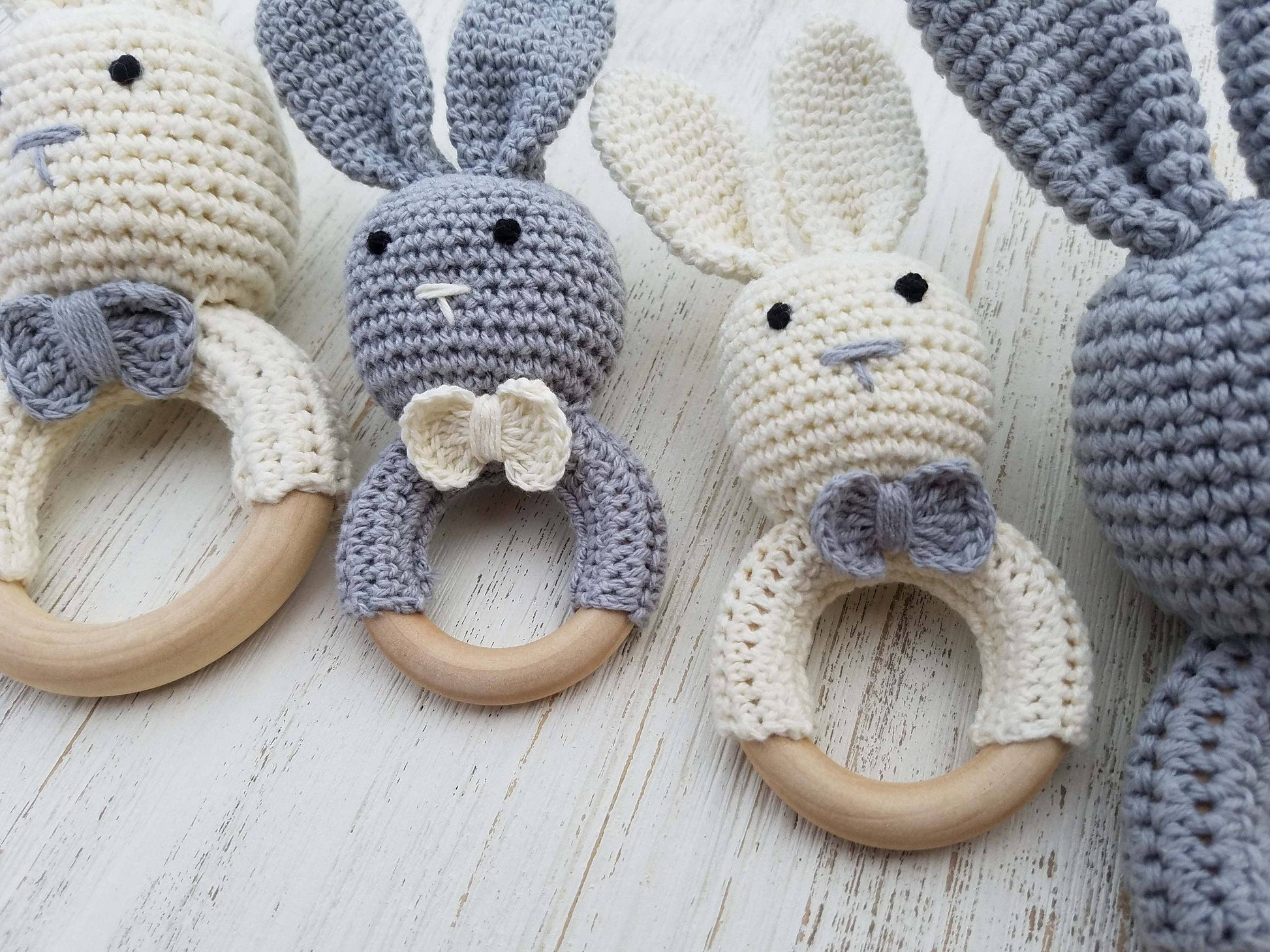 Crocheted bunny rattle toys with wooden rings on a light wooden surface