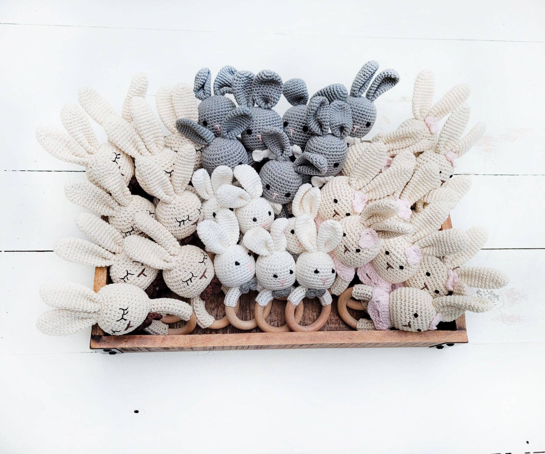 Collection of crochet bunny toys in various colors on a wooden tray.
