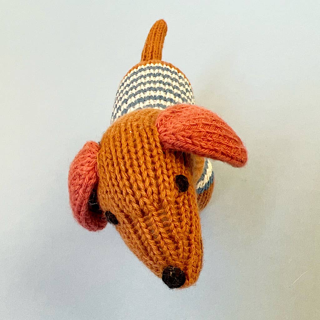 Knitted dachshund toy with striped pattern on a plain background