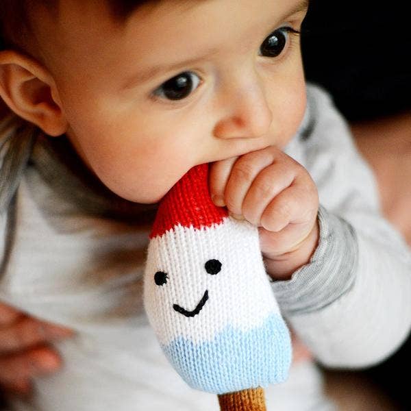Baby holding a knitted toy with a smiley face