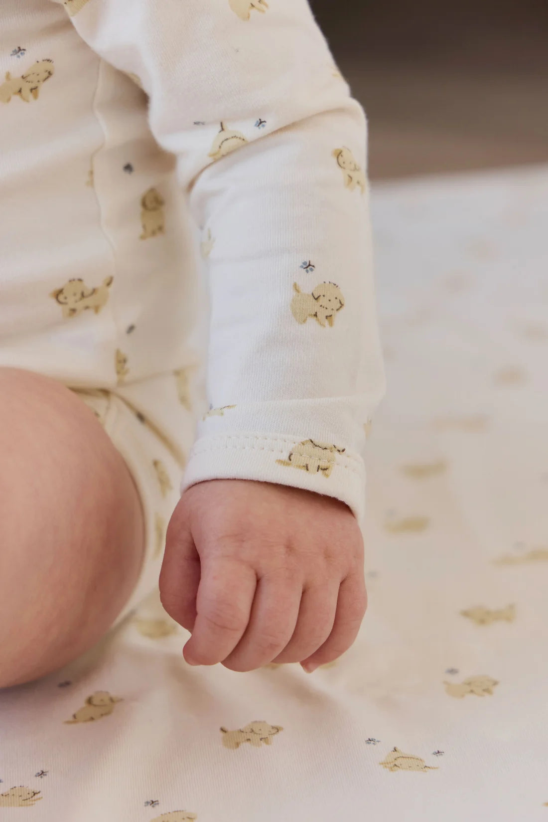 Baby's hand and foot wearing a floral outfit on a matching fabric background