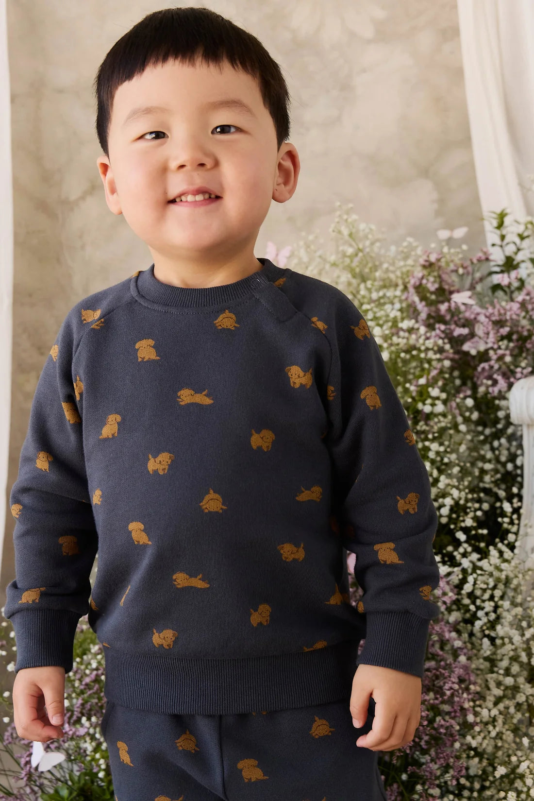 Child wearing a navy sweater with gold animal prints in a floral setting