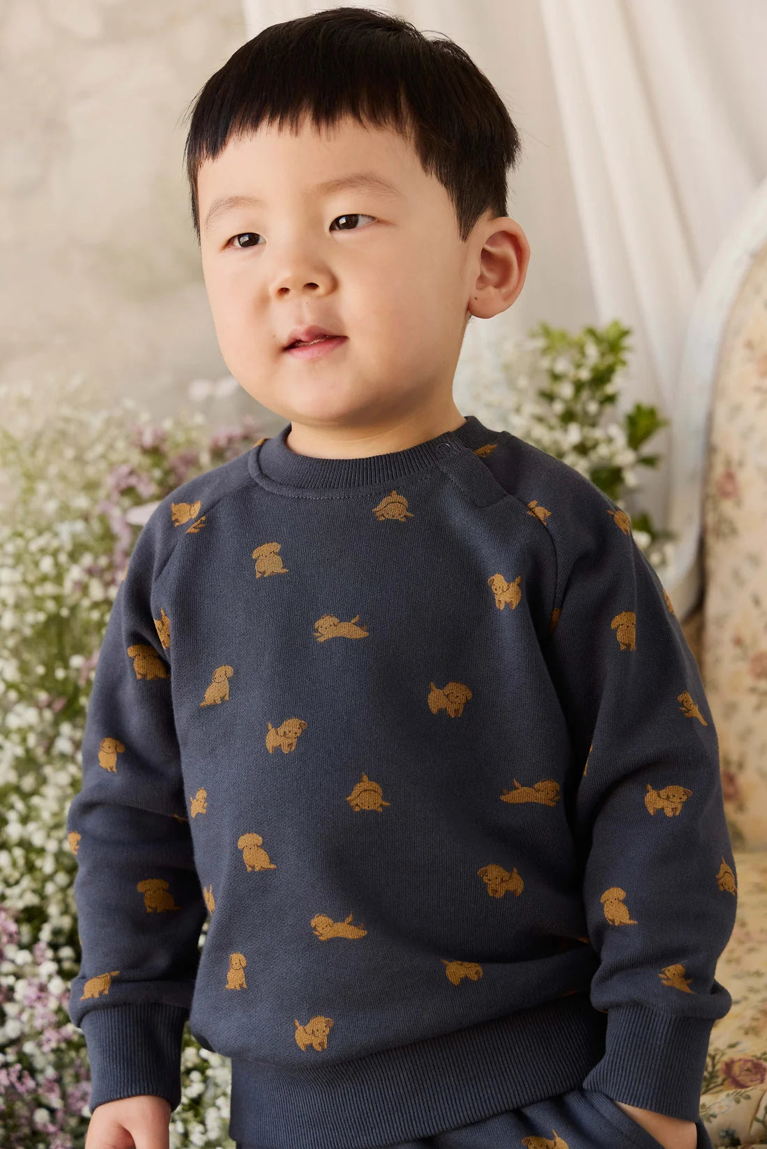 Child wearing a navy sweater with gold animal prints against a floral background