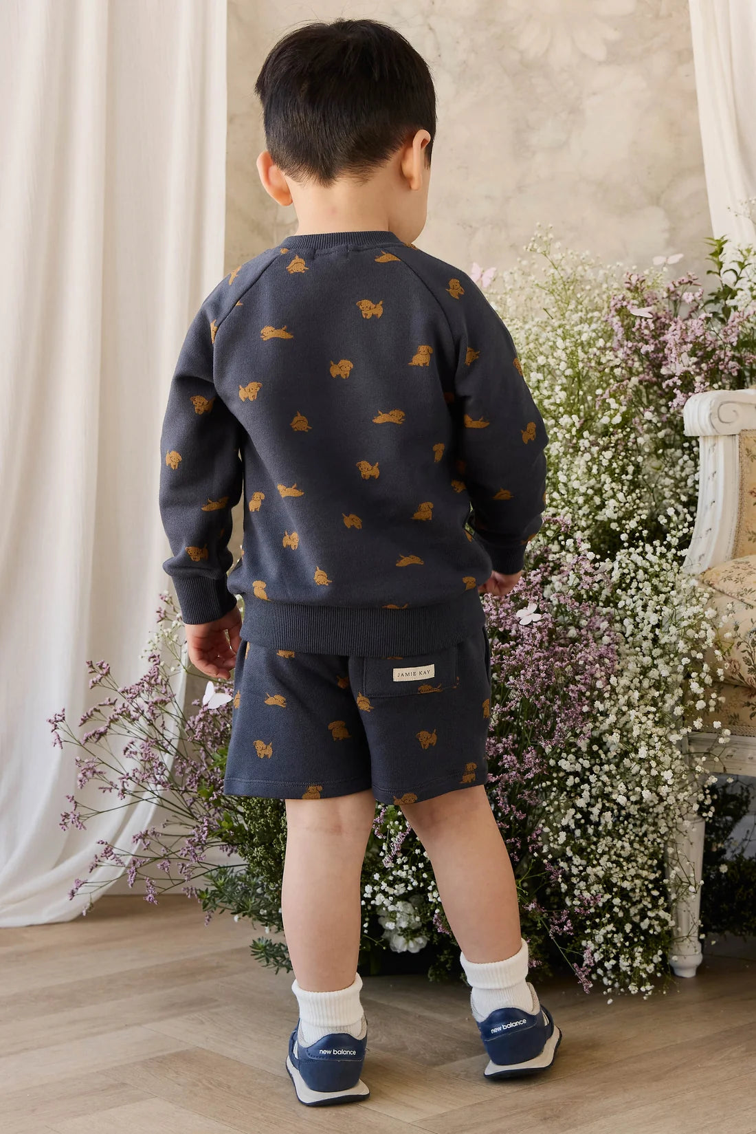 Child wearing a navy blue outfit with fox patterns in a decorated room with flowers.